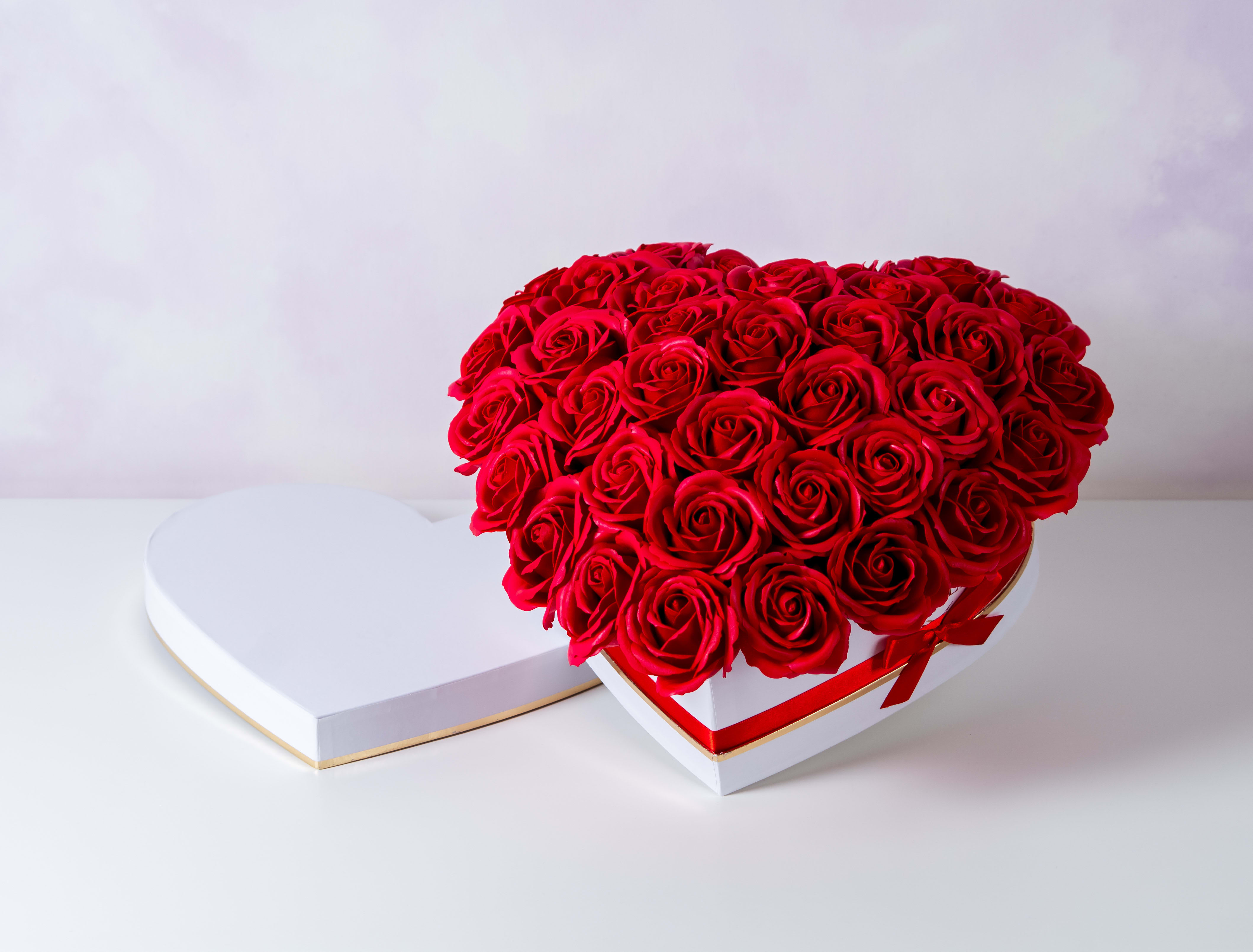 Heart-shaped box of red roses with a matching lid beside it