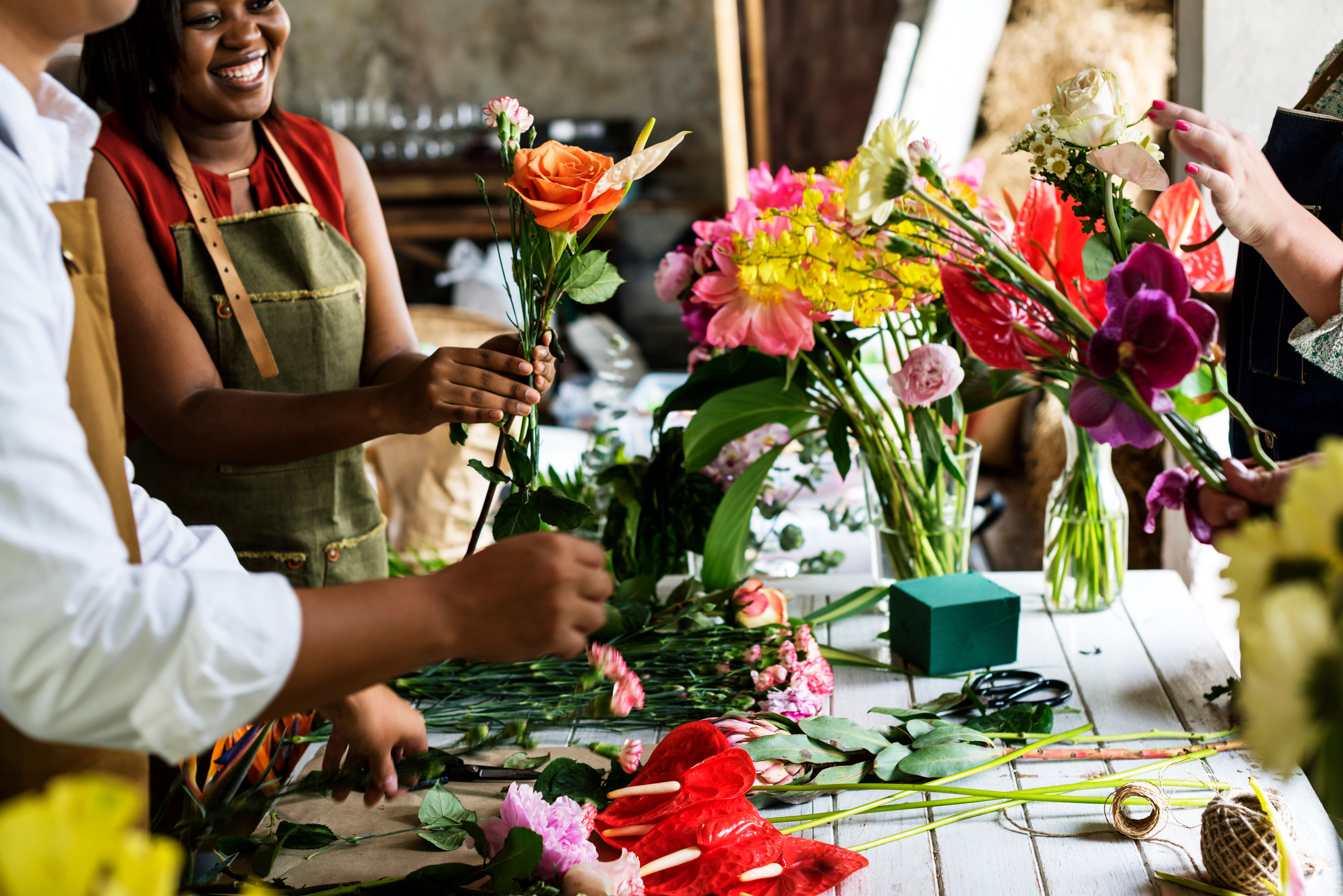 People arranging colorful flowers on a table in a workshop