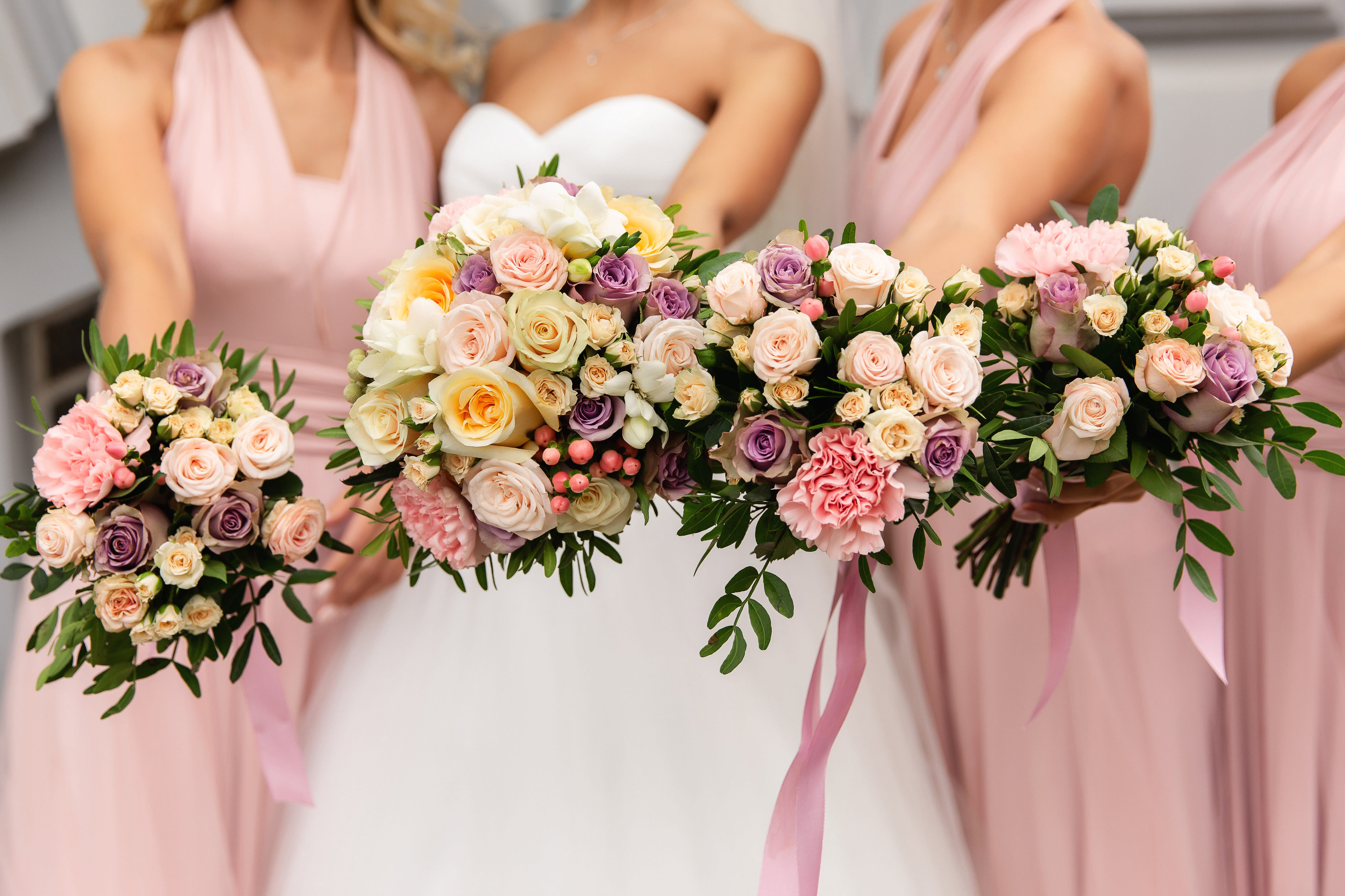 Bridesmaids holding pastel rose bouquets with pink dresses