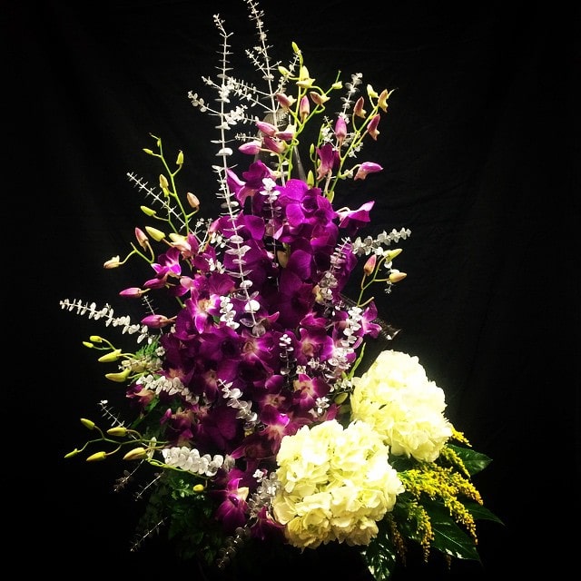 Purple orchids with white hydrangeas in a tall arrangement
