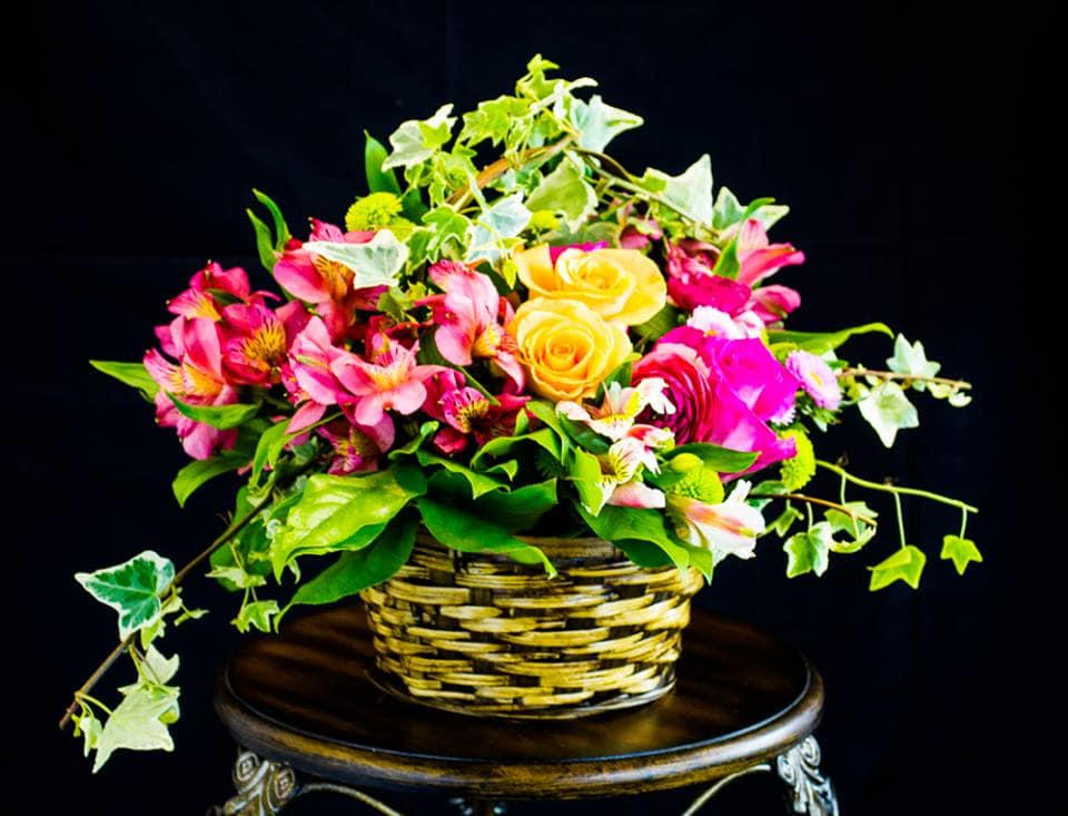 Basket arrangement of pink flowers and yellow roses with trailing ivy