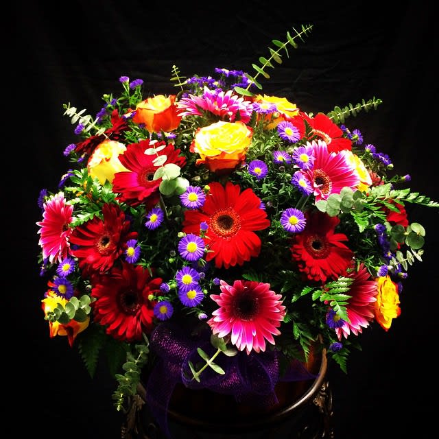 Bright mixed bouquet of gerbera daisies and roses with purple filler flowers