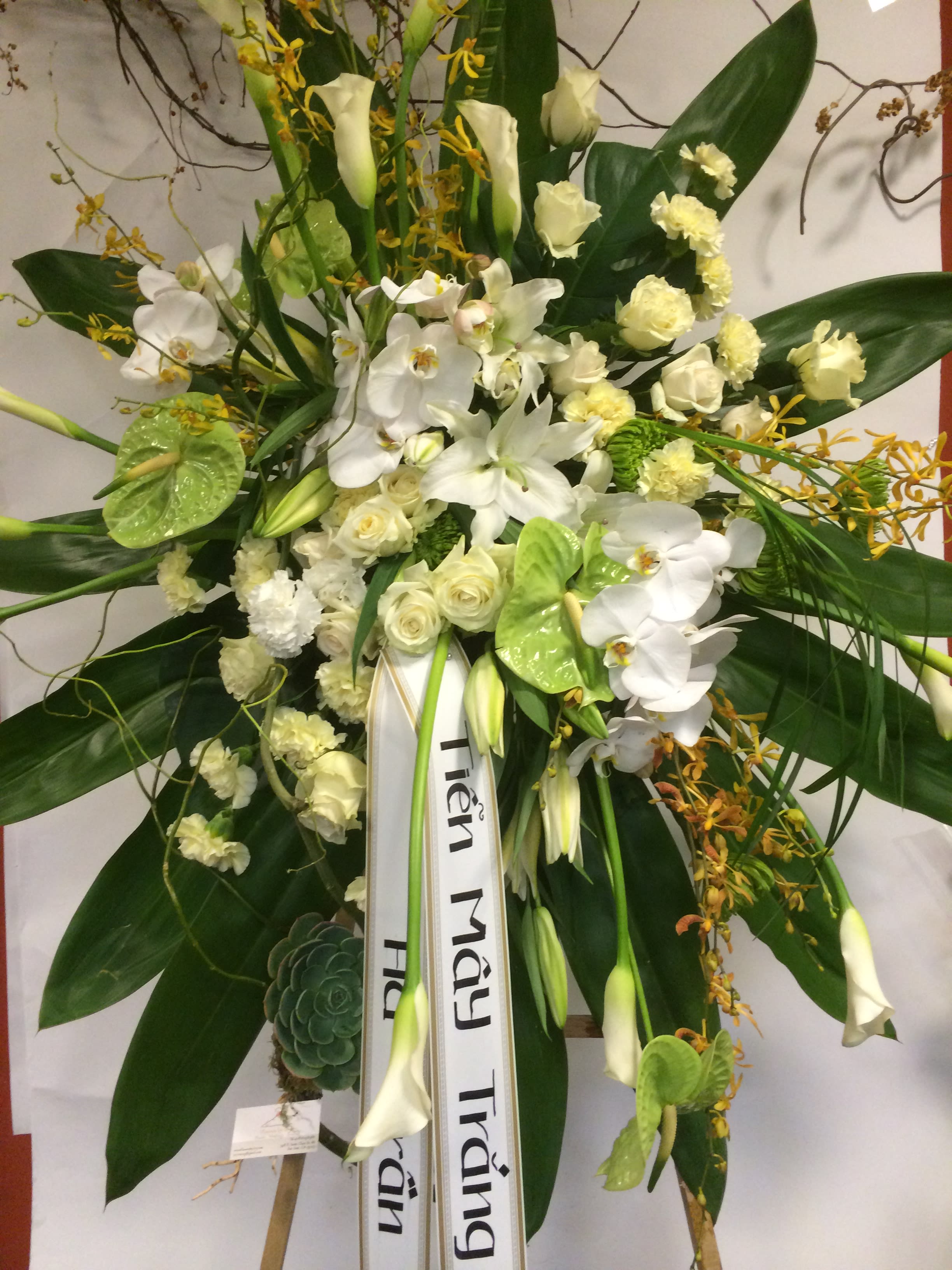 Large white floral standing spray with orchids, roses, and lilies