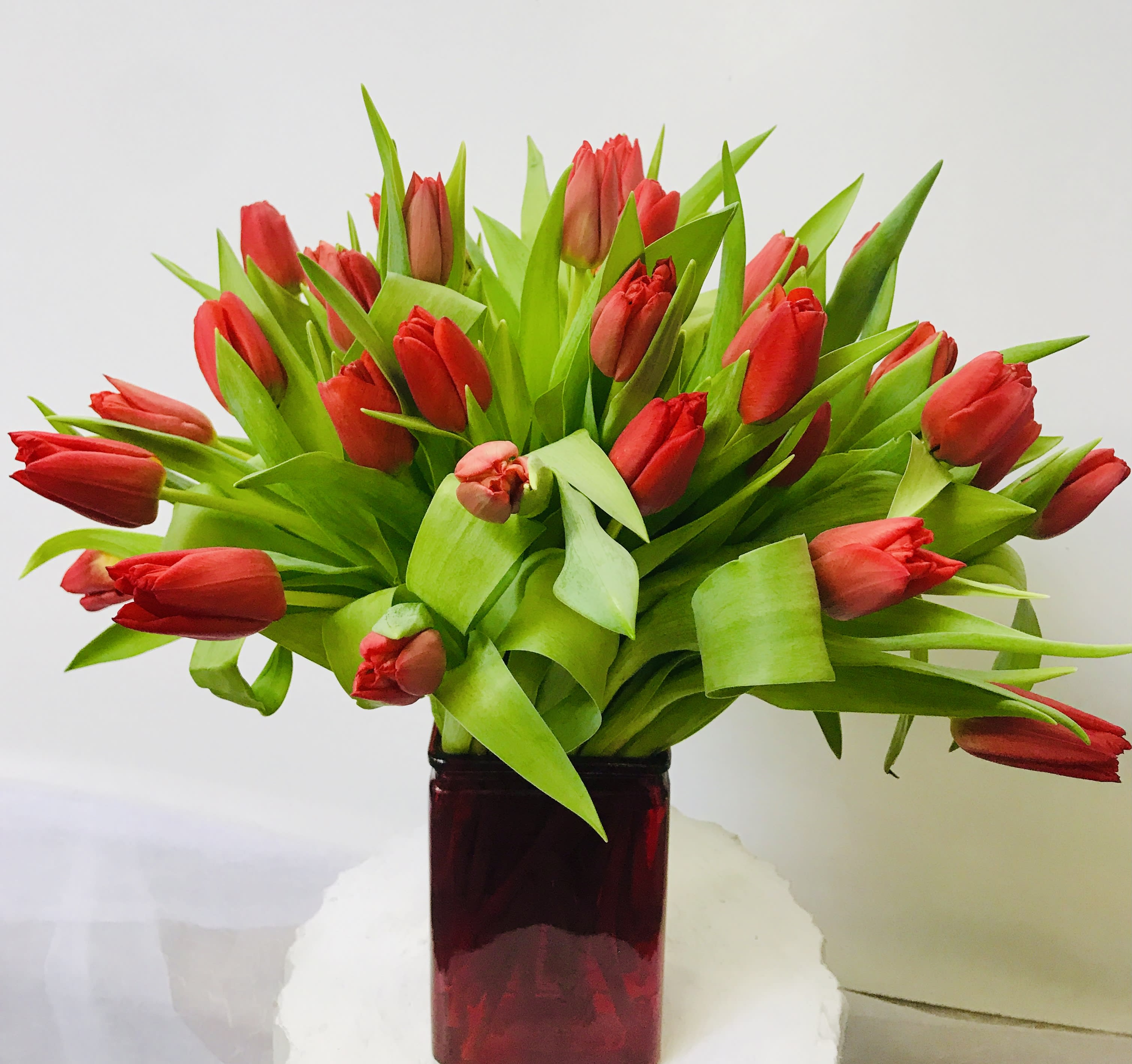 Red tulips arranged in a dark glass vase