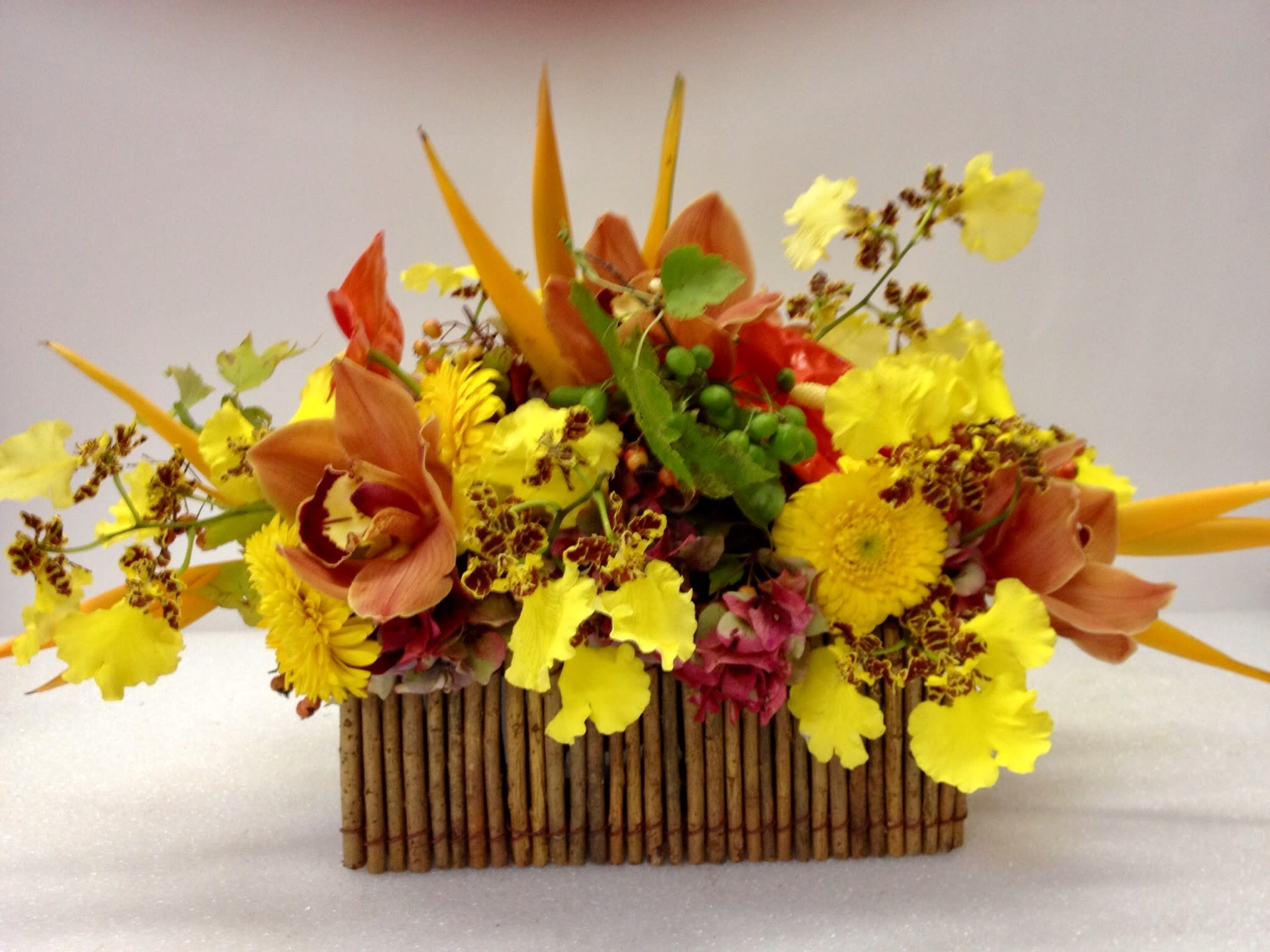 Bright yellow and orange floral arrangement in a rectangular wooden container