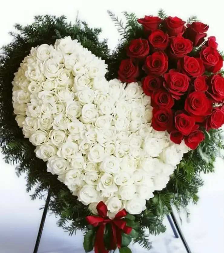 Heart-shaped standing arrangement of red and white roses with a red ribbon