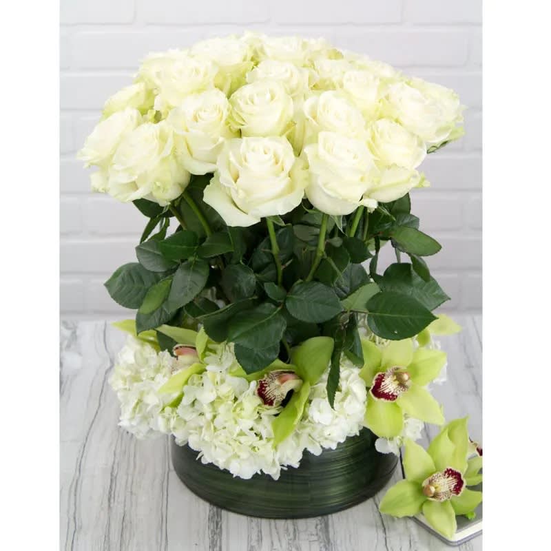 Showstopper - This definitely has the "WOW" factor. Absolutely gorgeous tall White Roses are the focal point of this uniquely styled arrangement. Full clusters of white Hydrangeas and beautiful Green Orchids encircle the base of the stems creating a divine design. A very special gift for that important person in your life, or special occasion. 