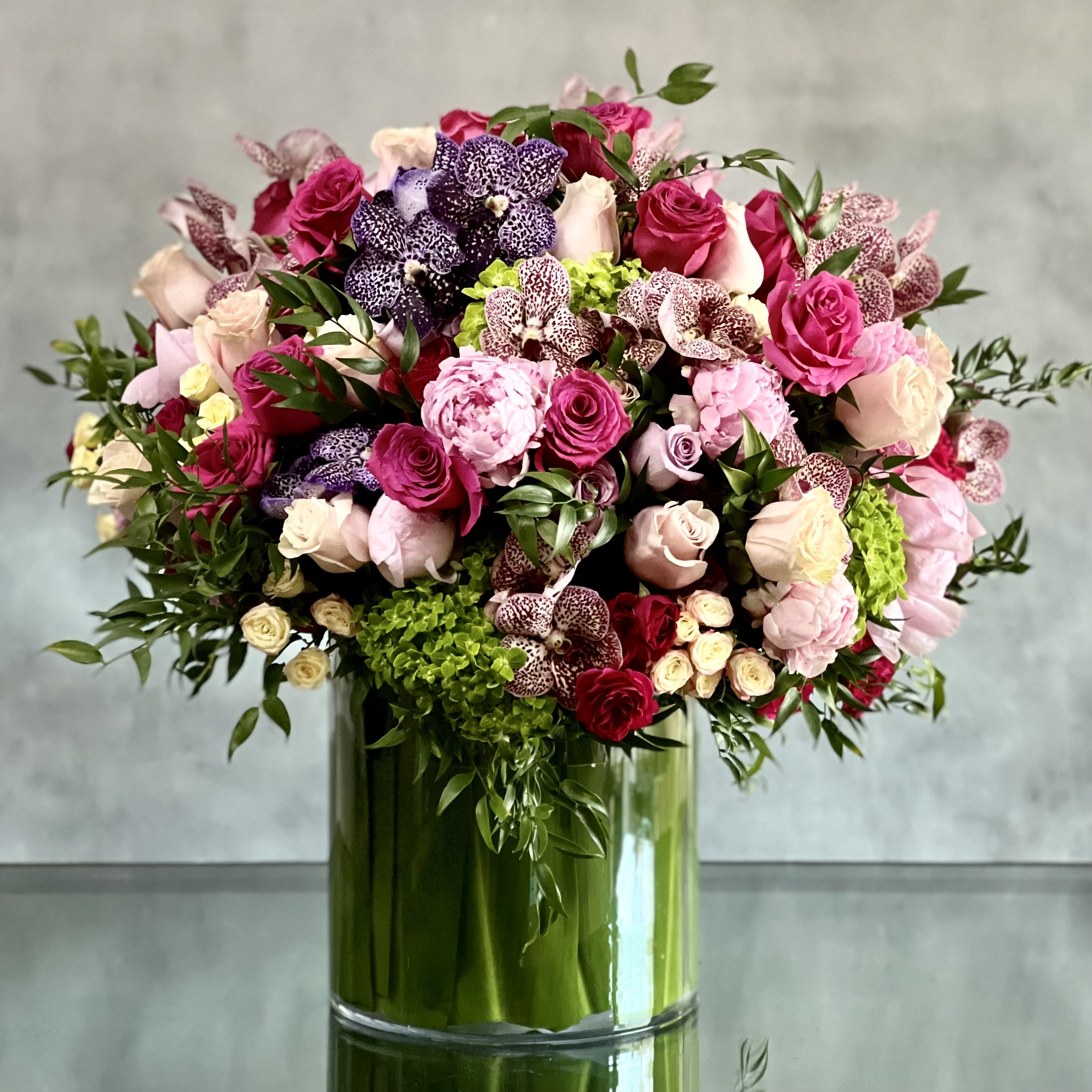 What a Delight - Pastels and vivid bright florals are featured in this sophisticated design. Lovely shades of pink, lavender and white Roses and spray roses, pink peonies, variety of spotted Orchids are combined with seasonal blooms. All colors and botanicals float above the green Hydrangeas at its base. Its a huge arrangement for any occasions.