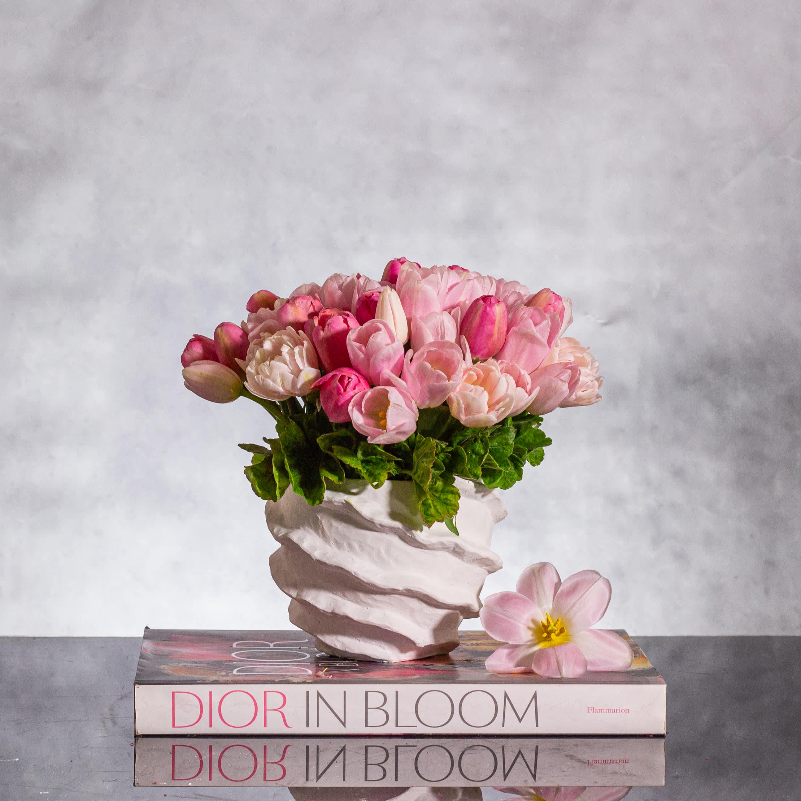 Springtime Symphony - Embrace the essence of spring with our exquisite arrangement featuring 50 pink variety tulips displayed in a sleek modern ceramic vase. Perfectly suited for the season, this floral ensemble stands at approximately 9 inches tall and 9 inches wide, creating a striking presence wherever it is placed.  Allow the delicate beauty of pink tulips to bring a touch of freshness and vibrancy to your space. The perfect choice for springtime celebrations, this arrangement is expertly crafted to exude a sense of renewal and elegance. With Beverly Hills Florist offering same-day delivery, you can bring the spirit of spring right to your doorstep with ease and style.