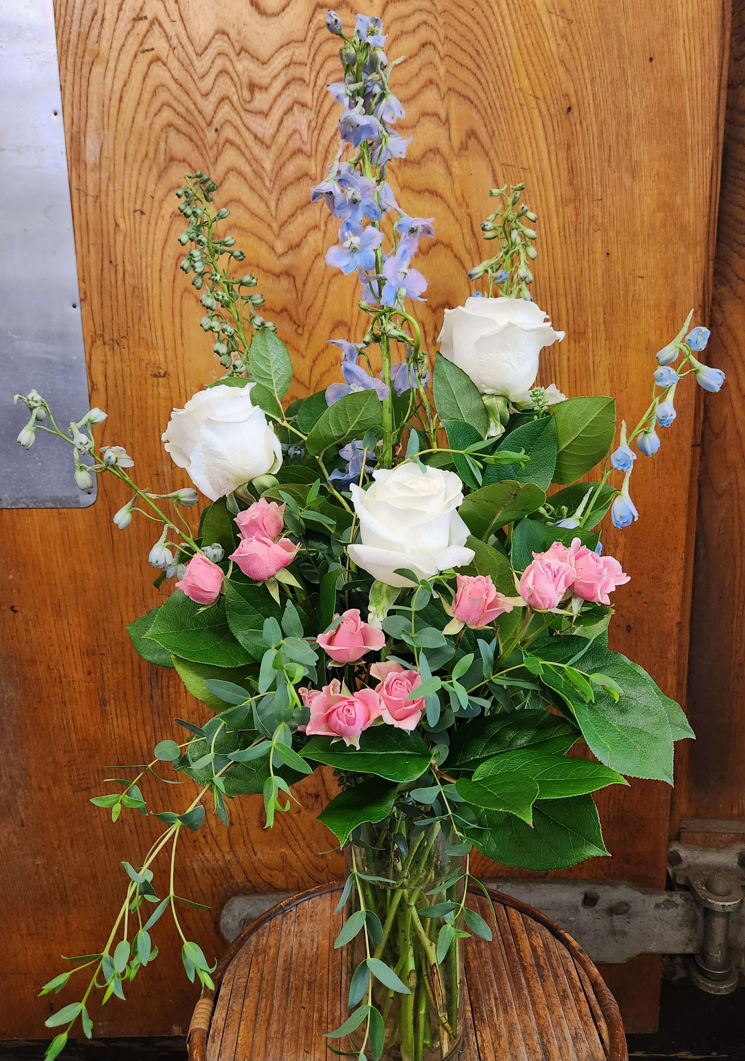 Pink and white roses with blue delphinium in a glass vase