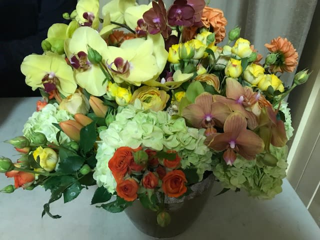 Mixed bouquet with orchids, hydrangeas, and roses in a dark vase
