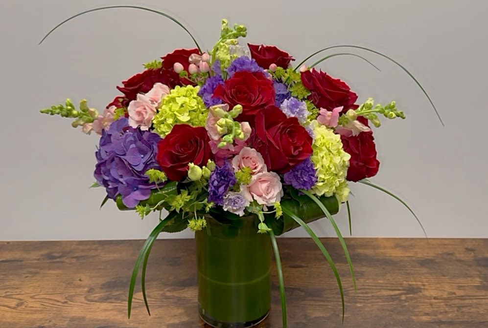 Red roses and purple hydrangeas in a green vase