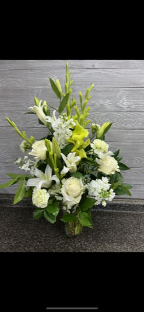 White and pale yellow floral arrangement in a clear glass vase