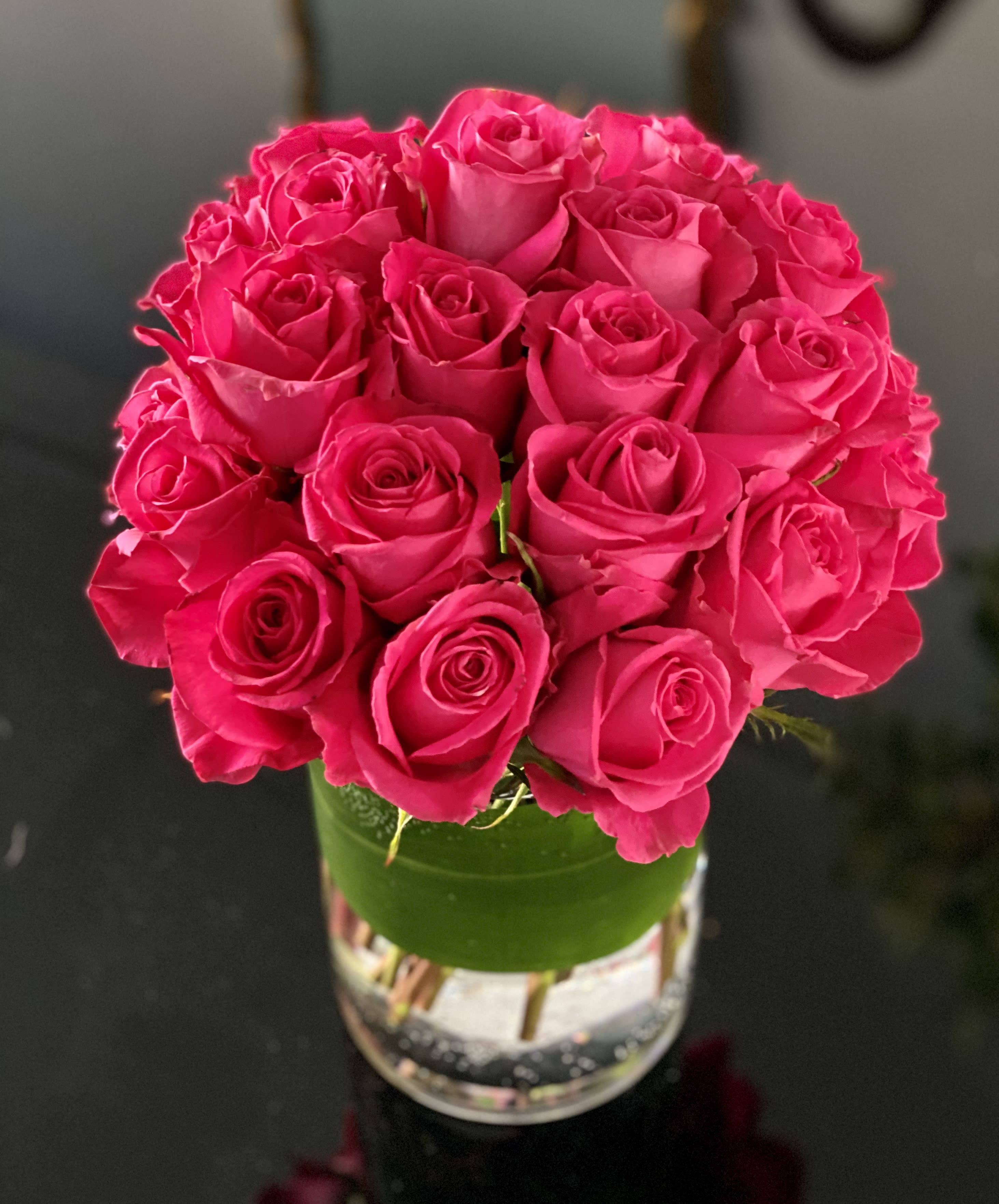 Kiko Roses Galore  - 25 Kiko Roses mounded in a clear glass vase wrapped in aspidistra leaf. Please note colors may vary depending on availability.