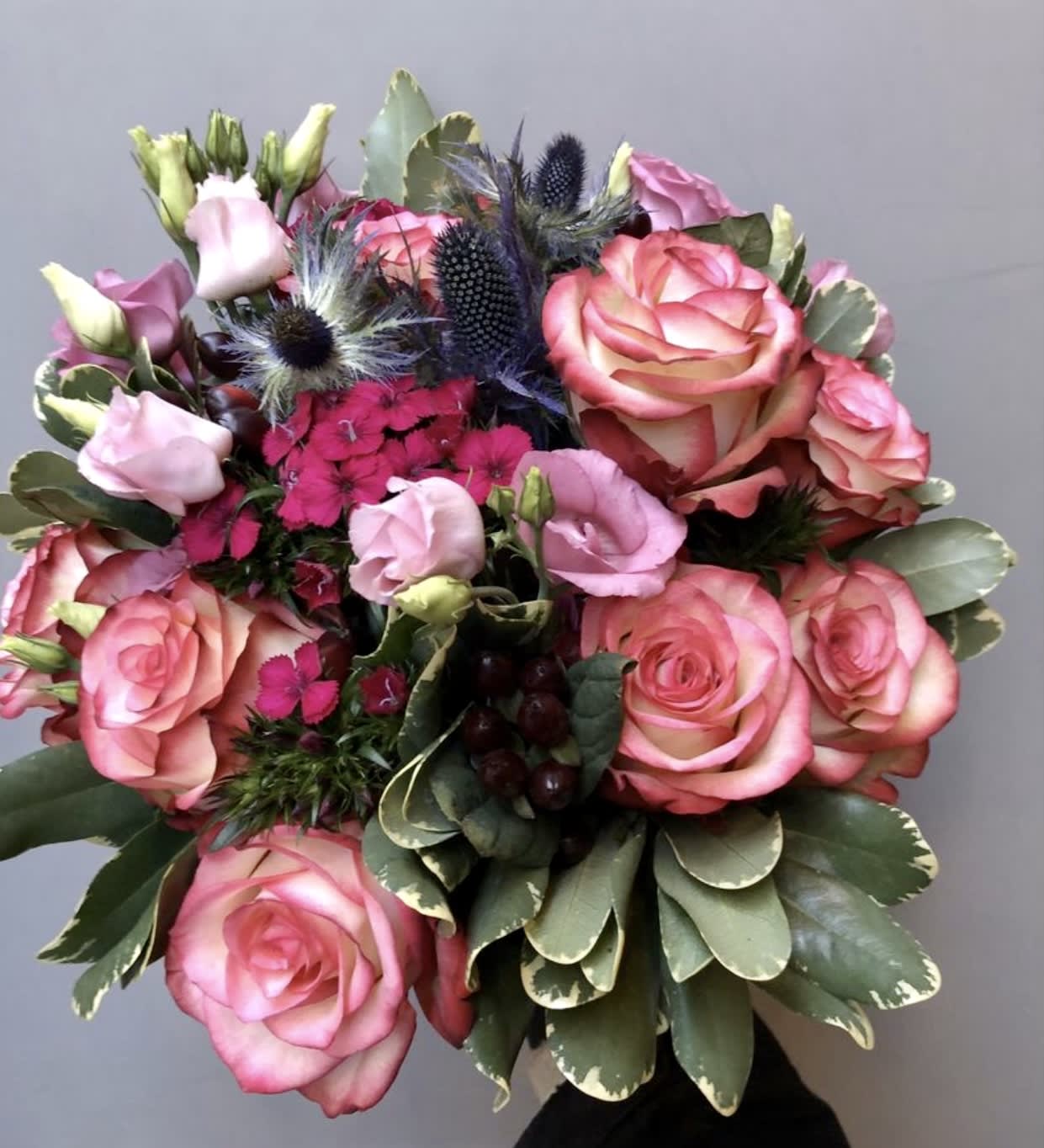 Bouquet of pink roses and lisianthus with dark thistle accents