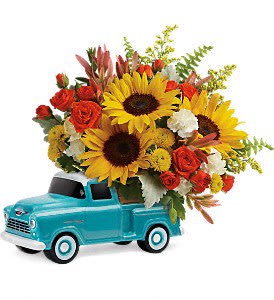 Sunflowers and red roses arranged in a turquoise toy truck