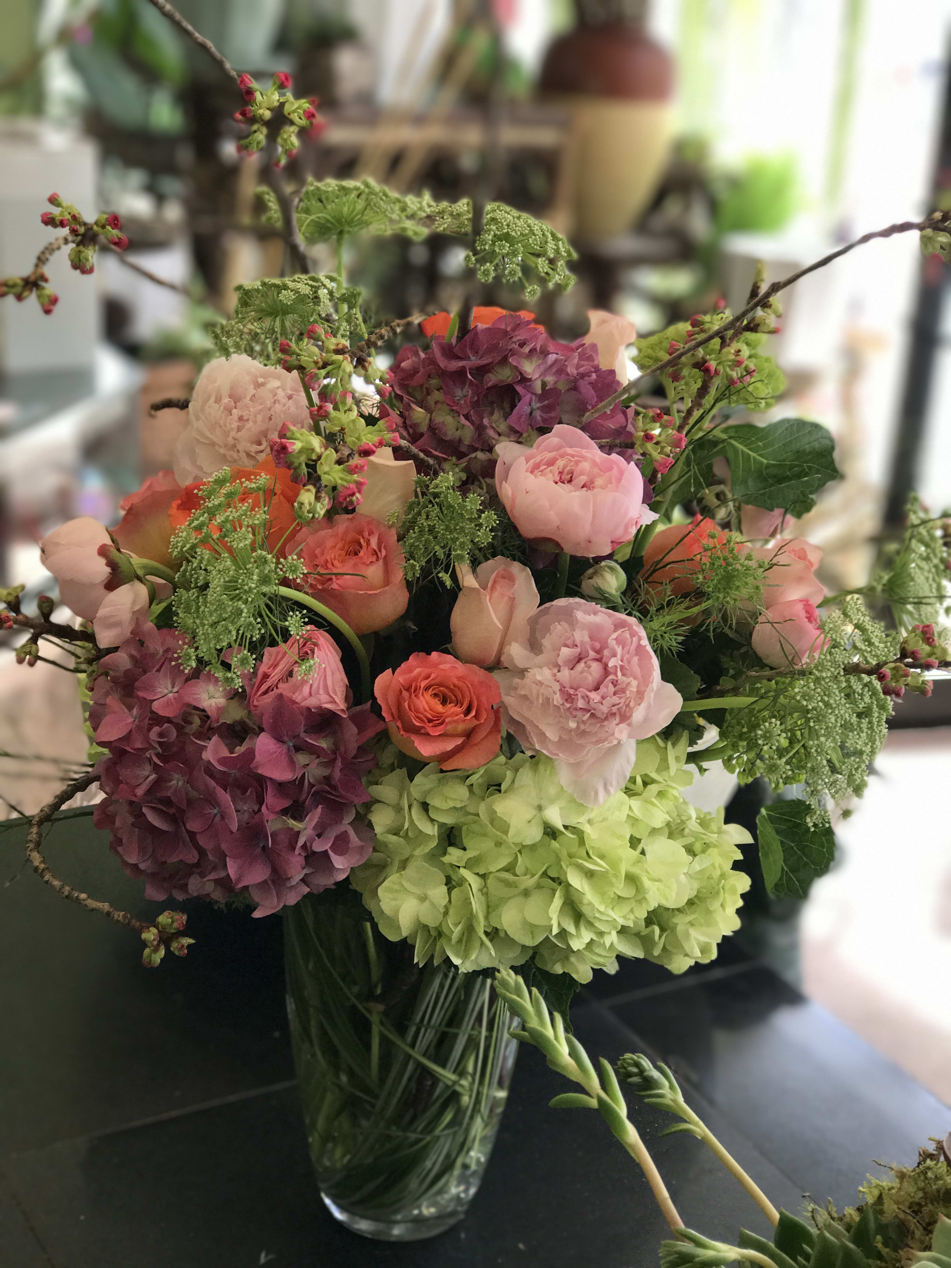 Mixed bouquet of pink, purple, and green flowers in a glass vase