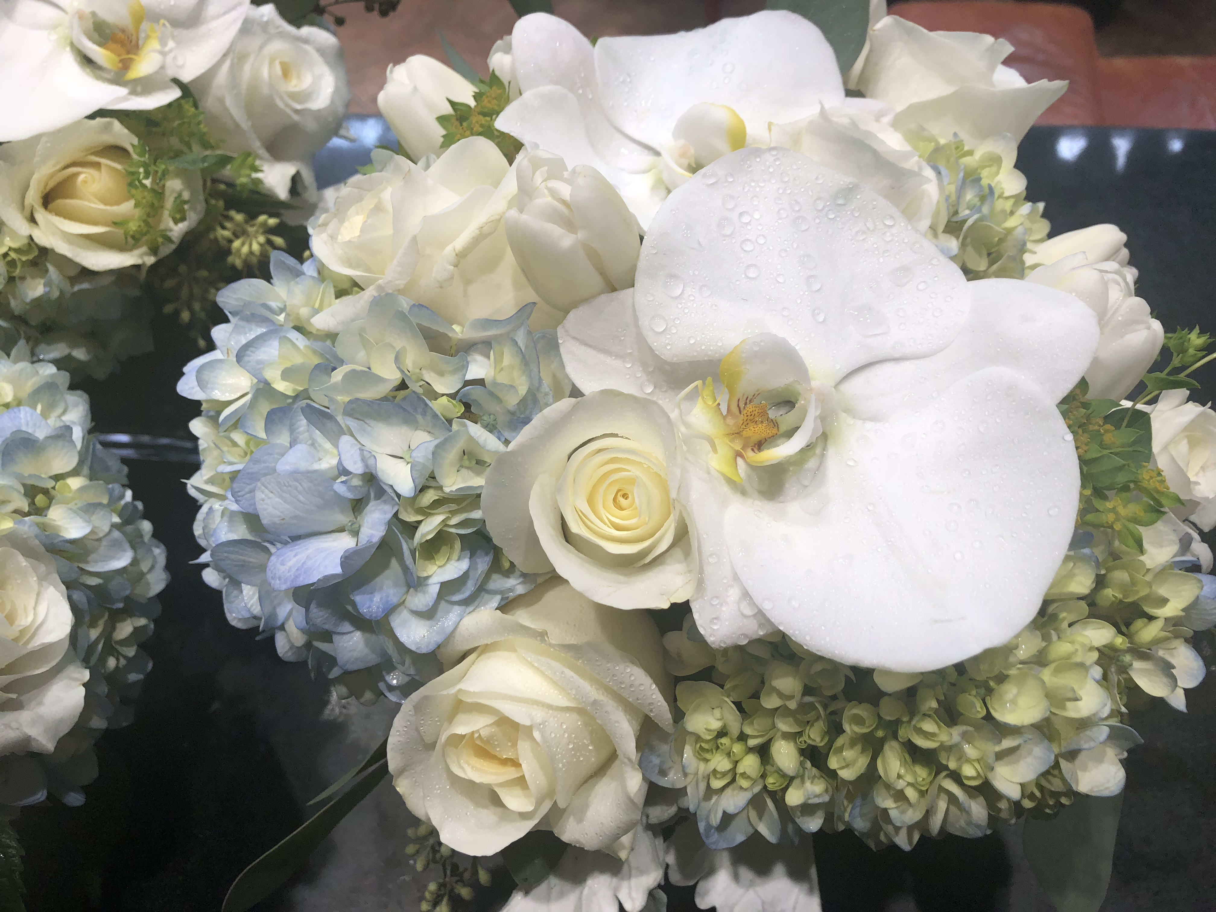 White orchids and roses with blue hydrangeas in a bouquet