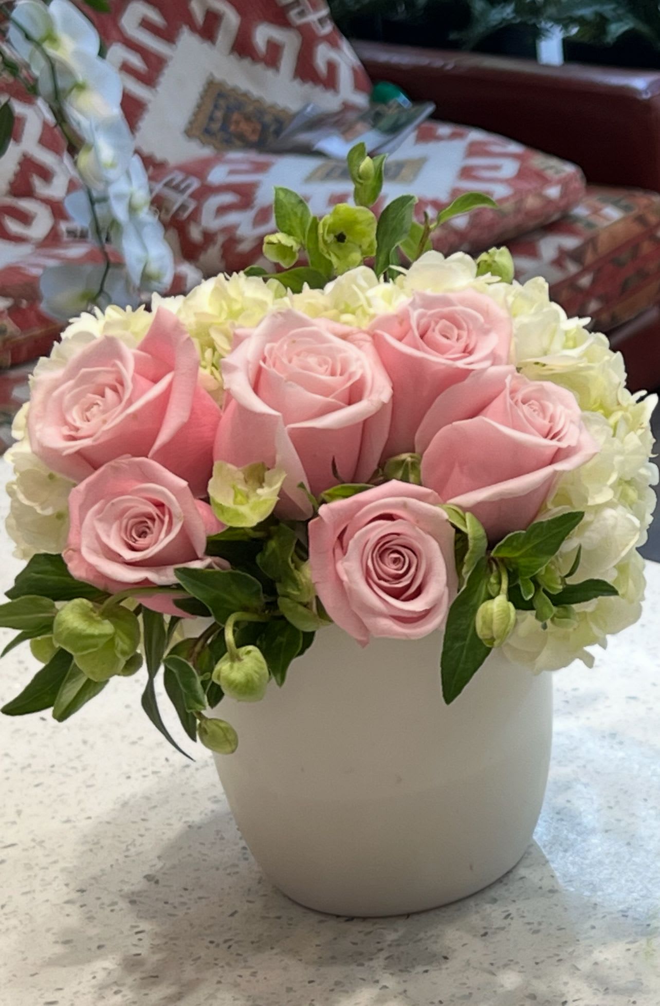Pink roses and white hydrangeas arranged in a white vase