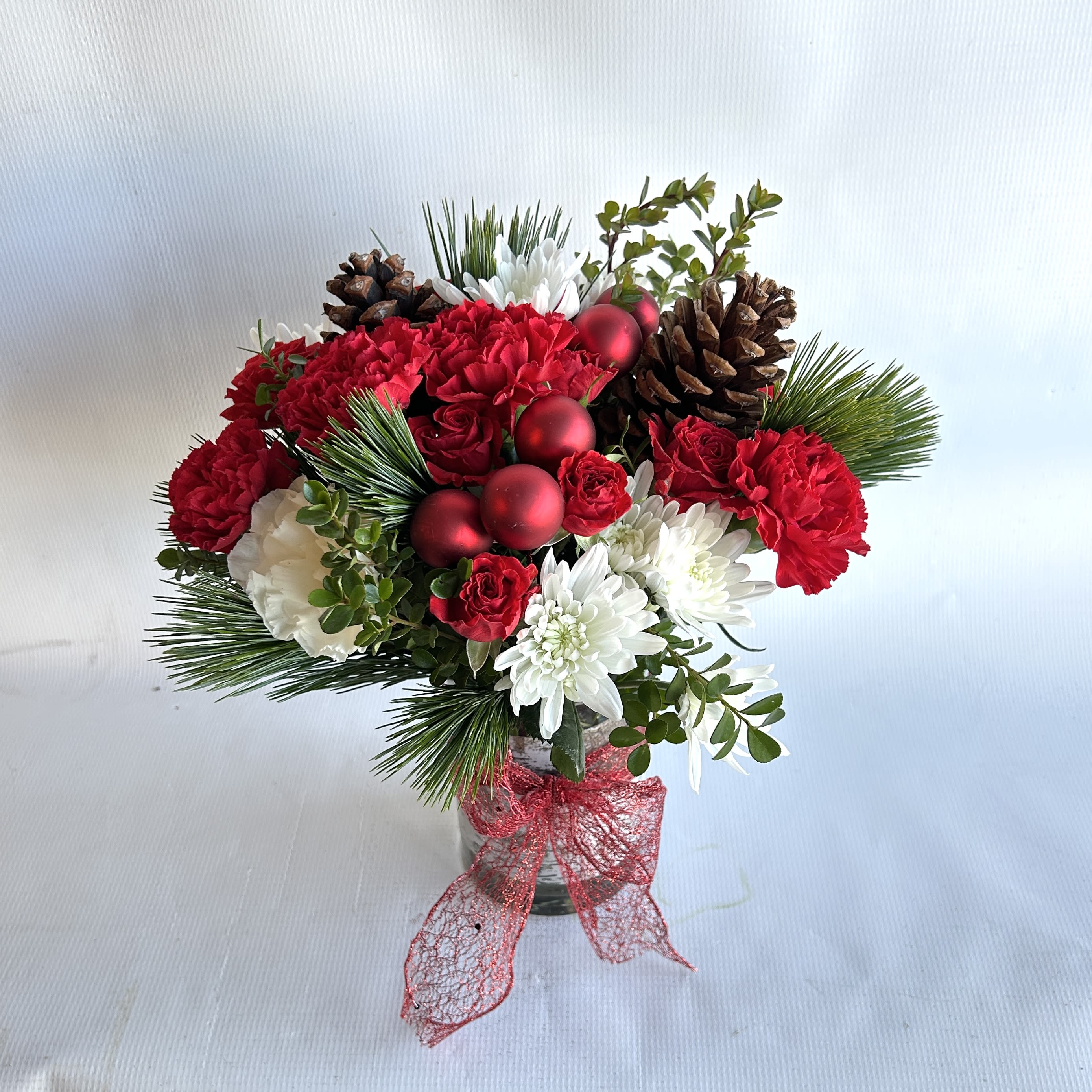 Pines &amp; Roses - This arrangement is set in a ceramic container, with red roses, hanging amaranthus, pine greenery, pine cones, and gold ornaments.  
