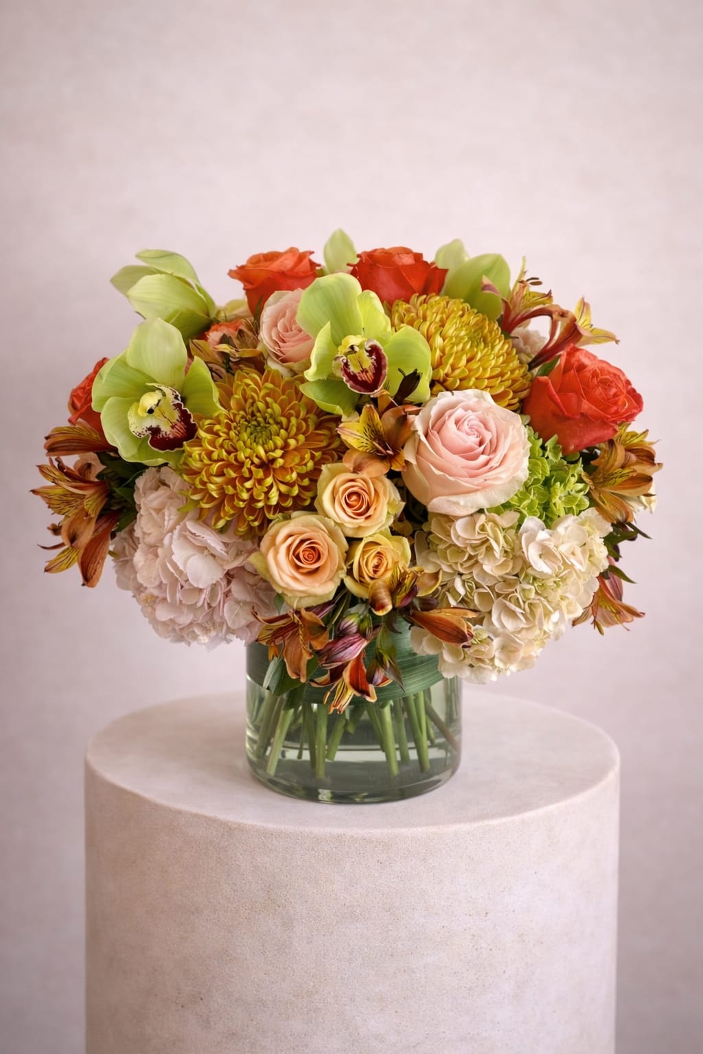 Mixed bouquet of roses, hydrangeas, orchids, and chrysanthemums in a glass vase