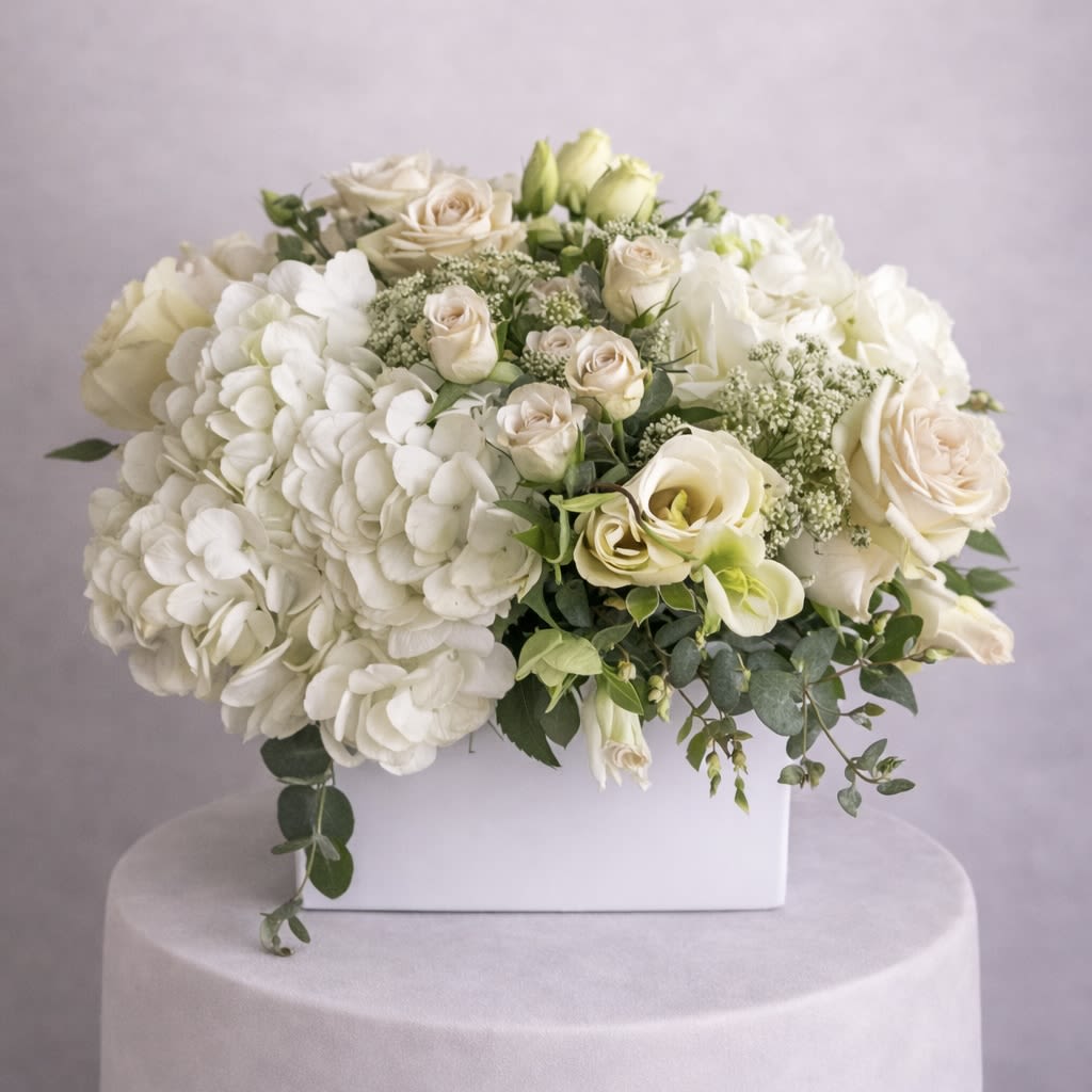 White floral arrangement with roses and hydrangeas in a white box