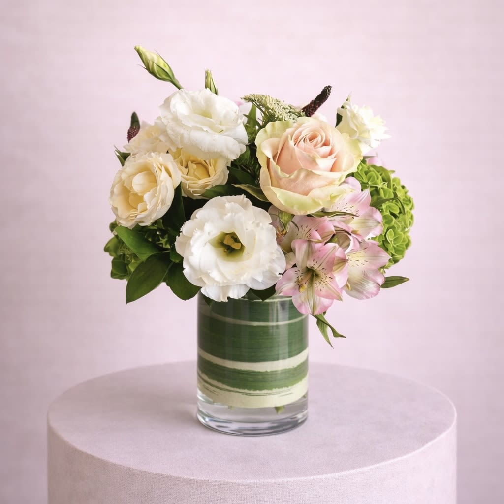Pink Lemonade - A lush and romantic floral arrangement featuring an exquisite blend of roses, lisianthus, veronica, hydrangeas, and alstroemeria in a delicate palette of soft pinks, warm peaches, and fresh greens.
