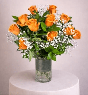 Arrangement of orange roses with white filler flowers in a clear glass cylinder vase