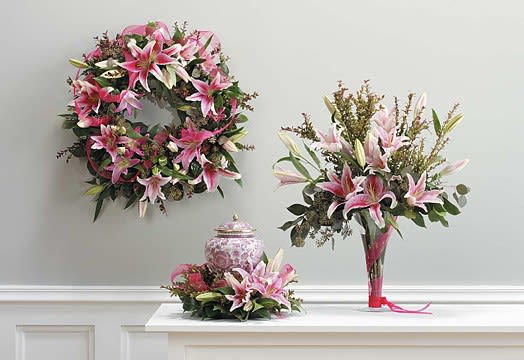 Pink lily arrangements with a matching wreath and vase centerpiece