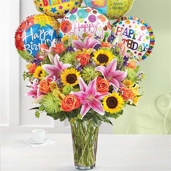 Birthday bouquet with balloons in a clear glass vase