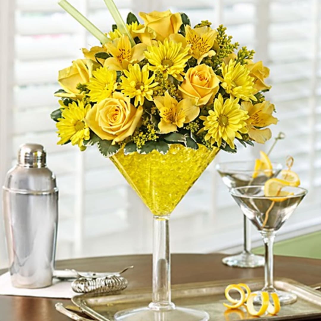 Yellow roses and daisies arranged in a martini glass centerpiece