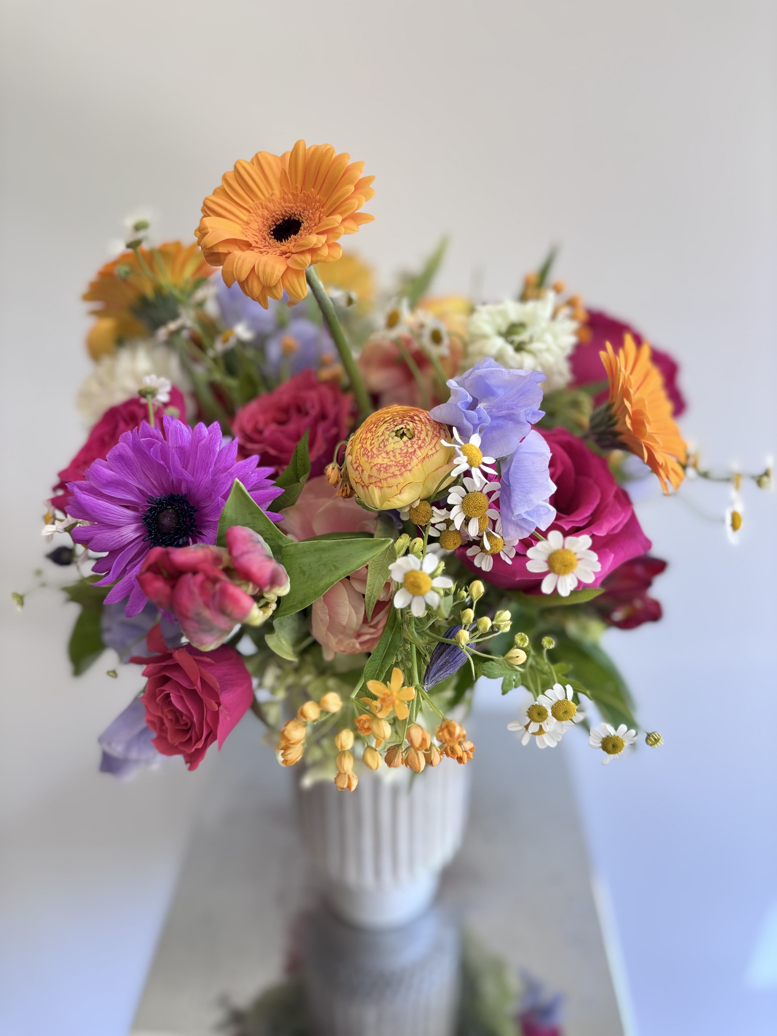 Blooms that Tell a Story - A gorgeous bouquet of abundant amount of premium spring flowers in a beautiful tall ceramic vase. This colorful flower gift offers a lovely selection of tulips, anemones, sweet peas, gerber daisies, hellebores, ranunculus, freesias, scabiosa, dianthus, and additional dainty blooms to fill the vase.