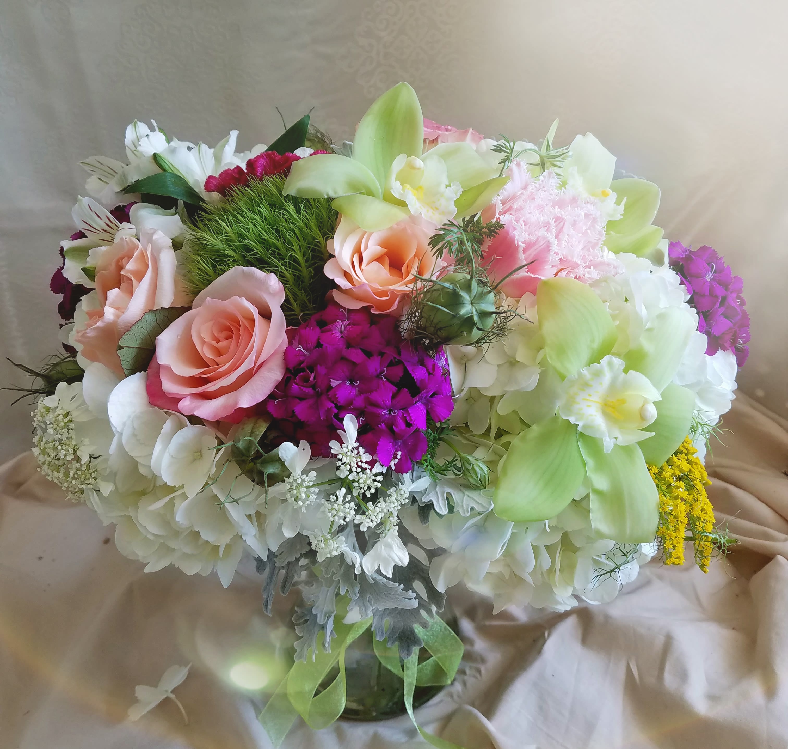Bouquet of pink roses, white hydrangeas, and green orchids in a glass vase