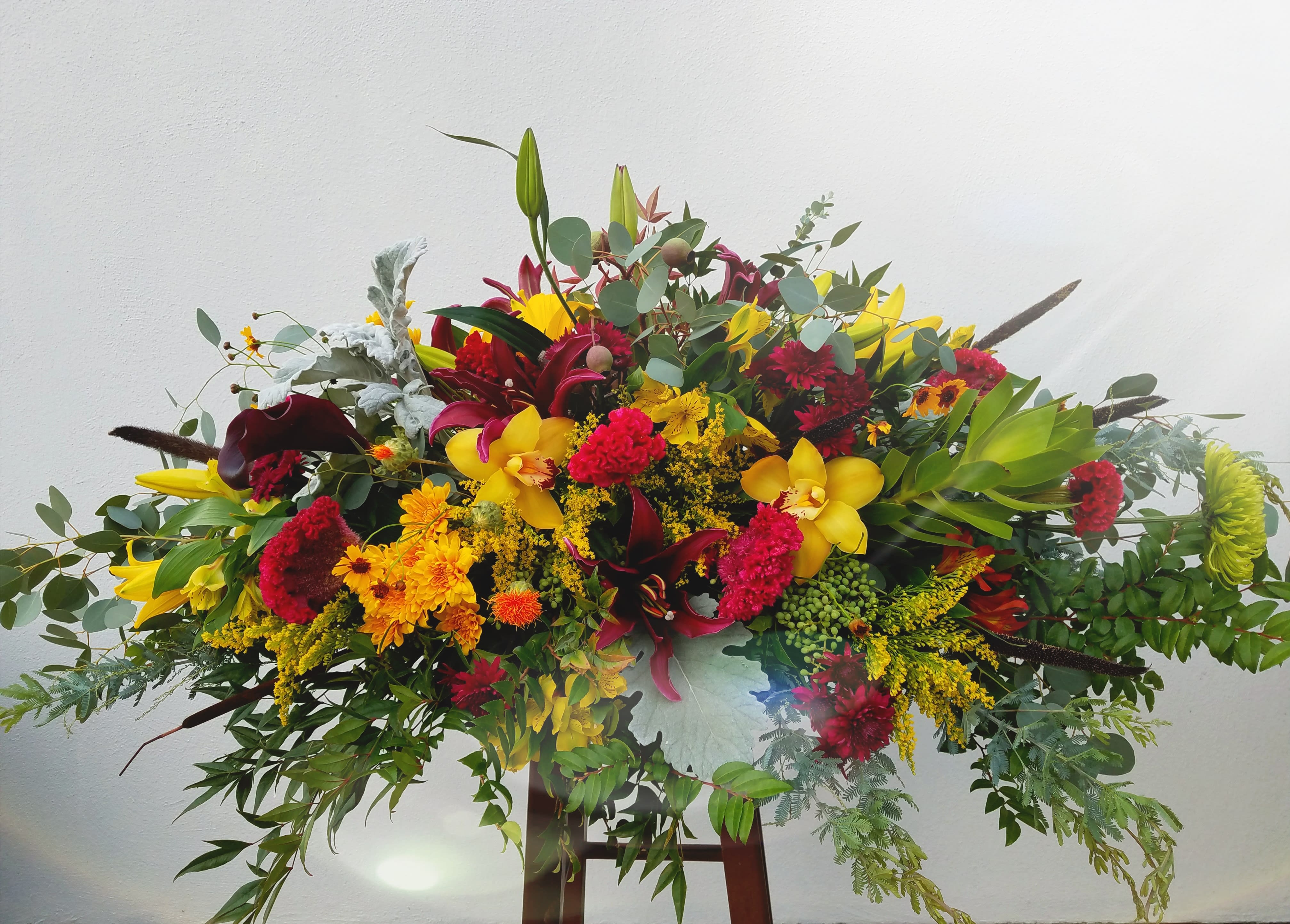 Large colorful floral arrangement with yellow, red, and burgundy blooms