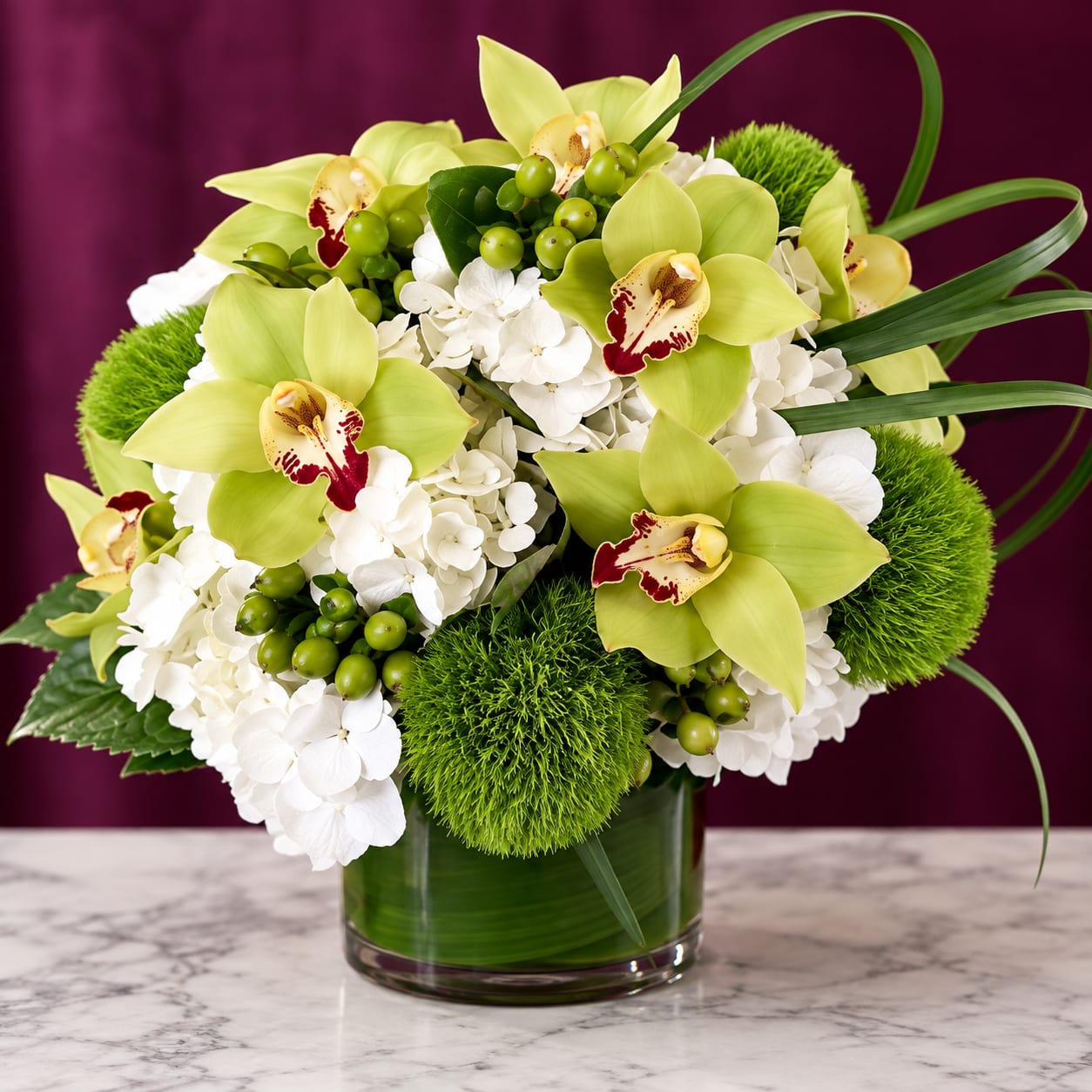 Green orchids and white hydrangeas in a glass vase with green accents