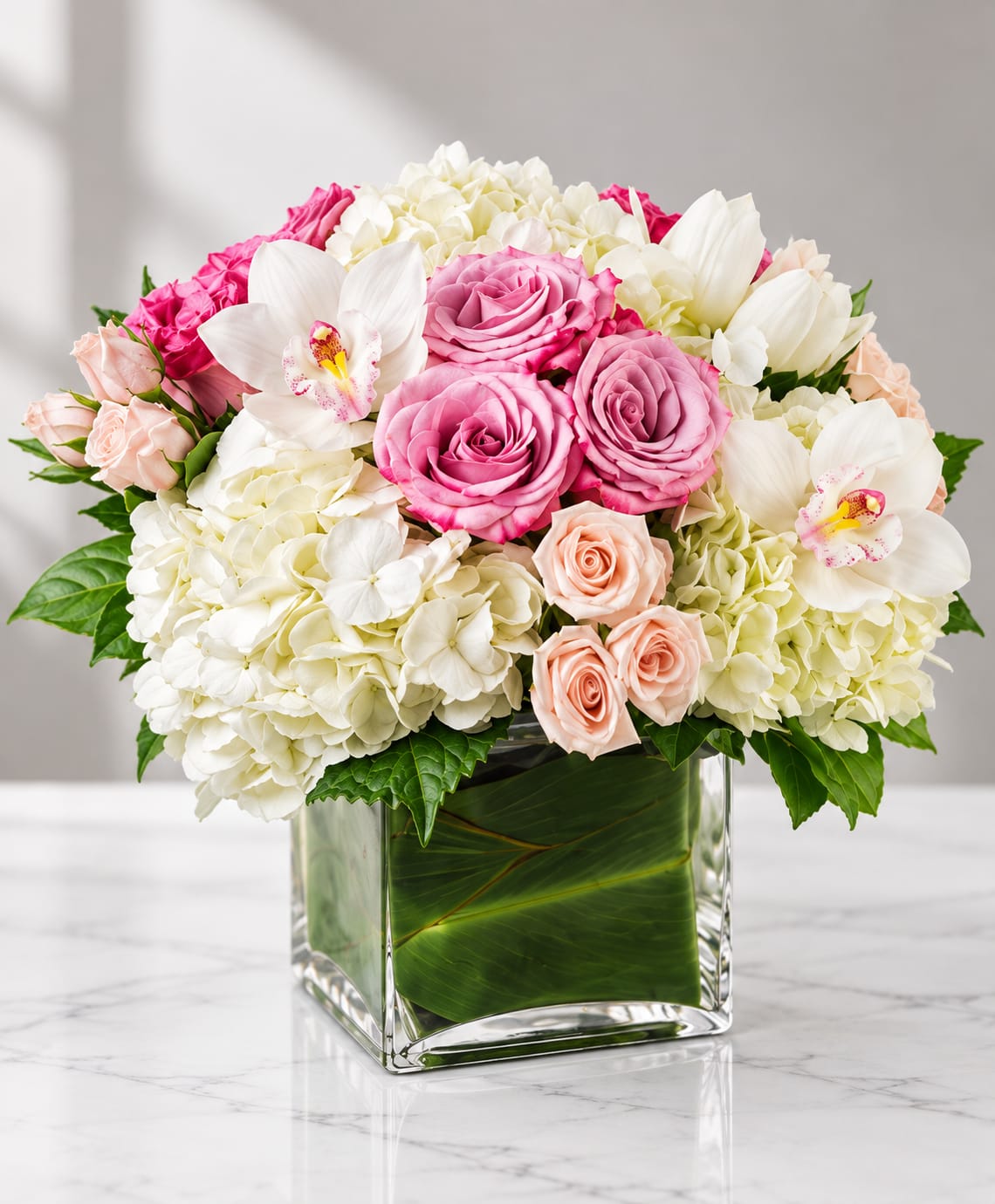 Pink and white flower arrangement in a square glass vase