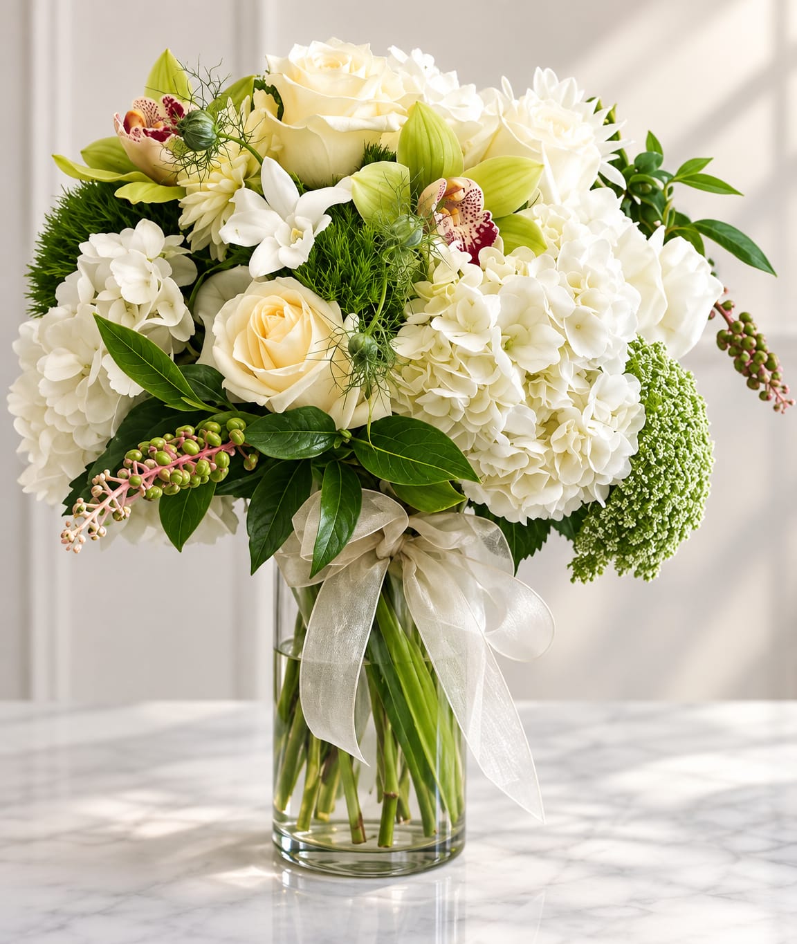 White and cream bouquet in a clear glass vase with a ribbon