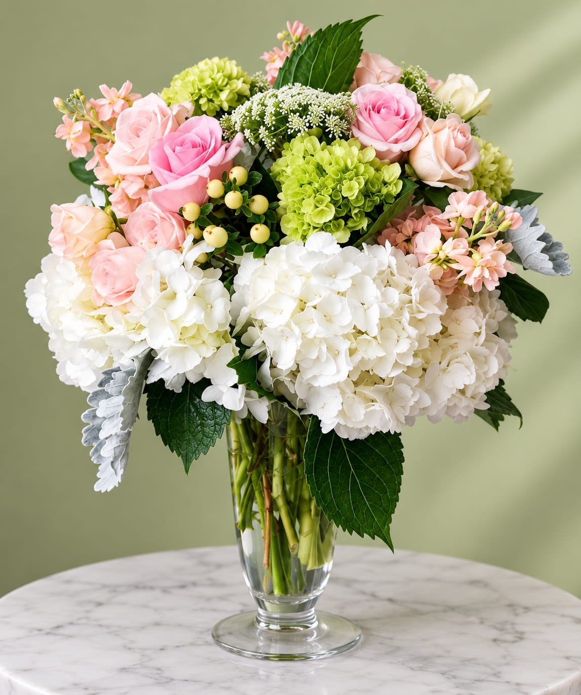 Pink and white roses with hydrangeas in a clear glass vase