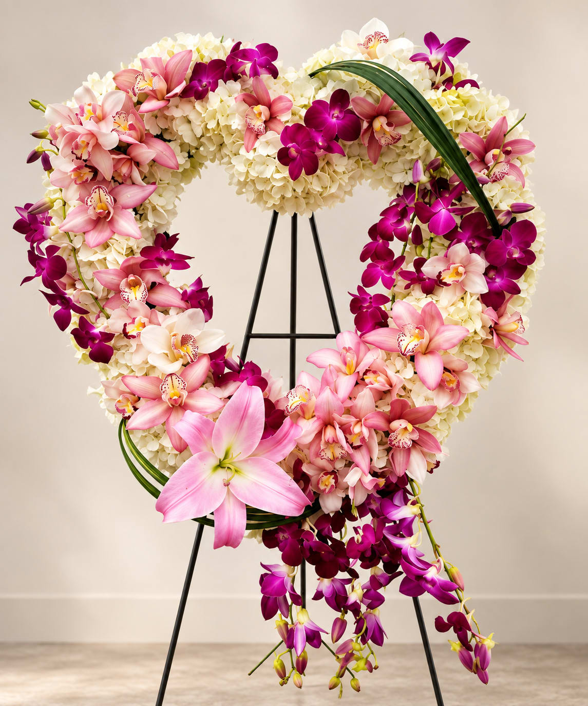 Heart-shaped floral wreath with pink and purple orchids on a stand