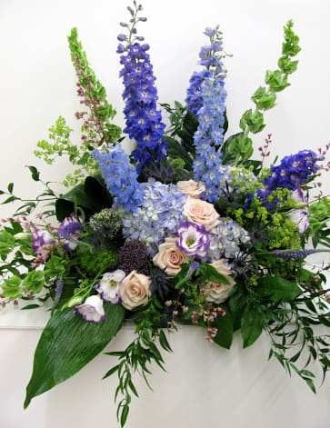 Tall floral arrangement with blue and lavender blooms and pale roses