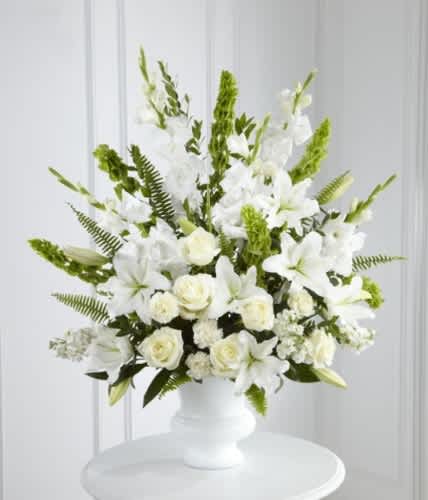 White floral arrangement in a white vase with green accents