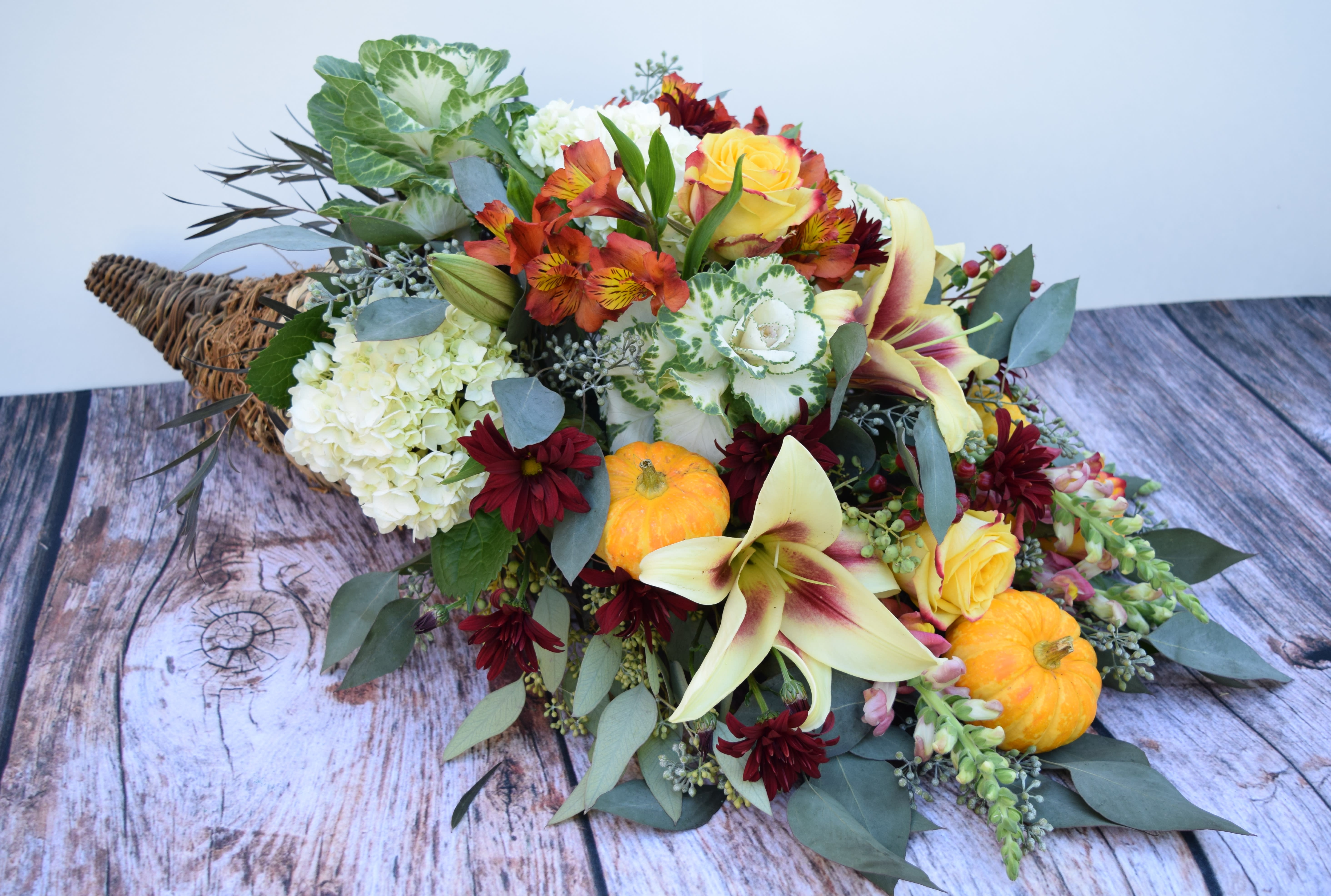 Autumn bouquet with lilies, roses, and small pumpkins