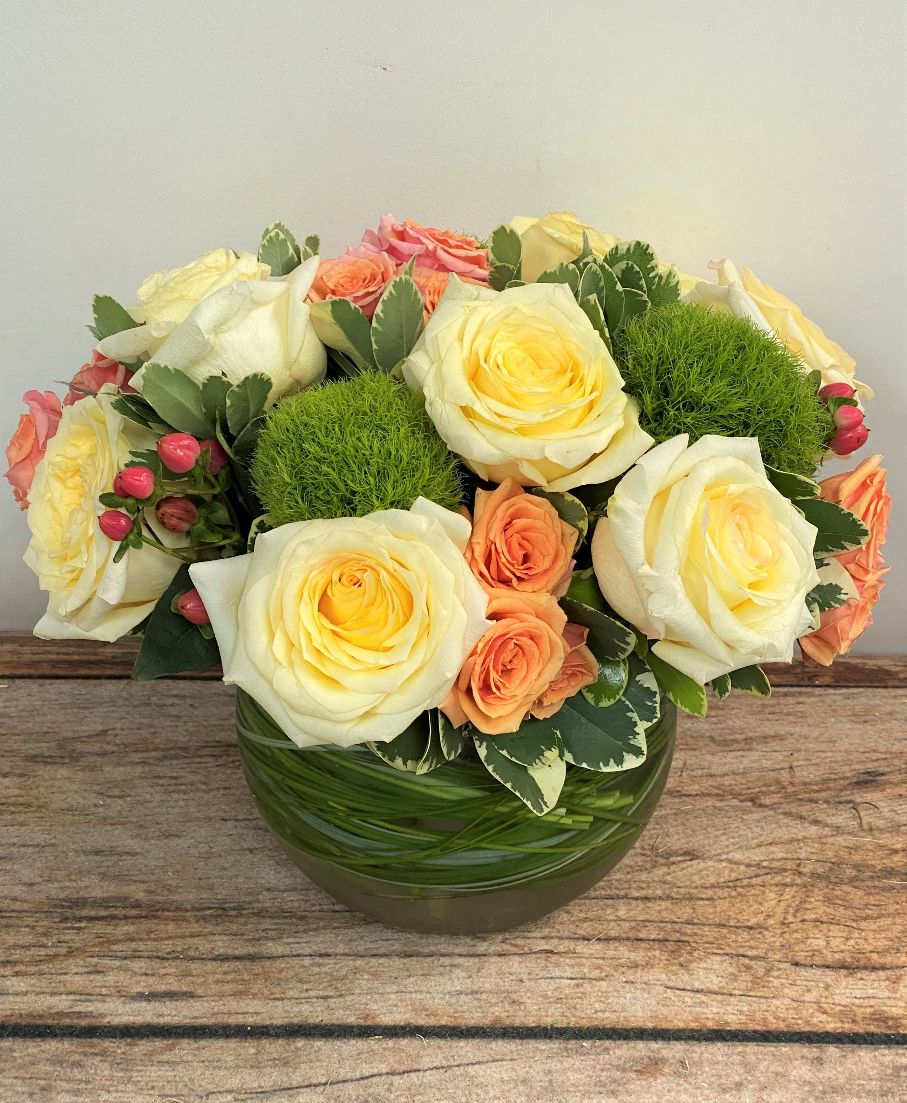 Cream and peach roses arranged in a round glass vase