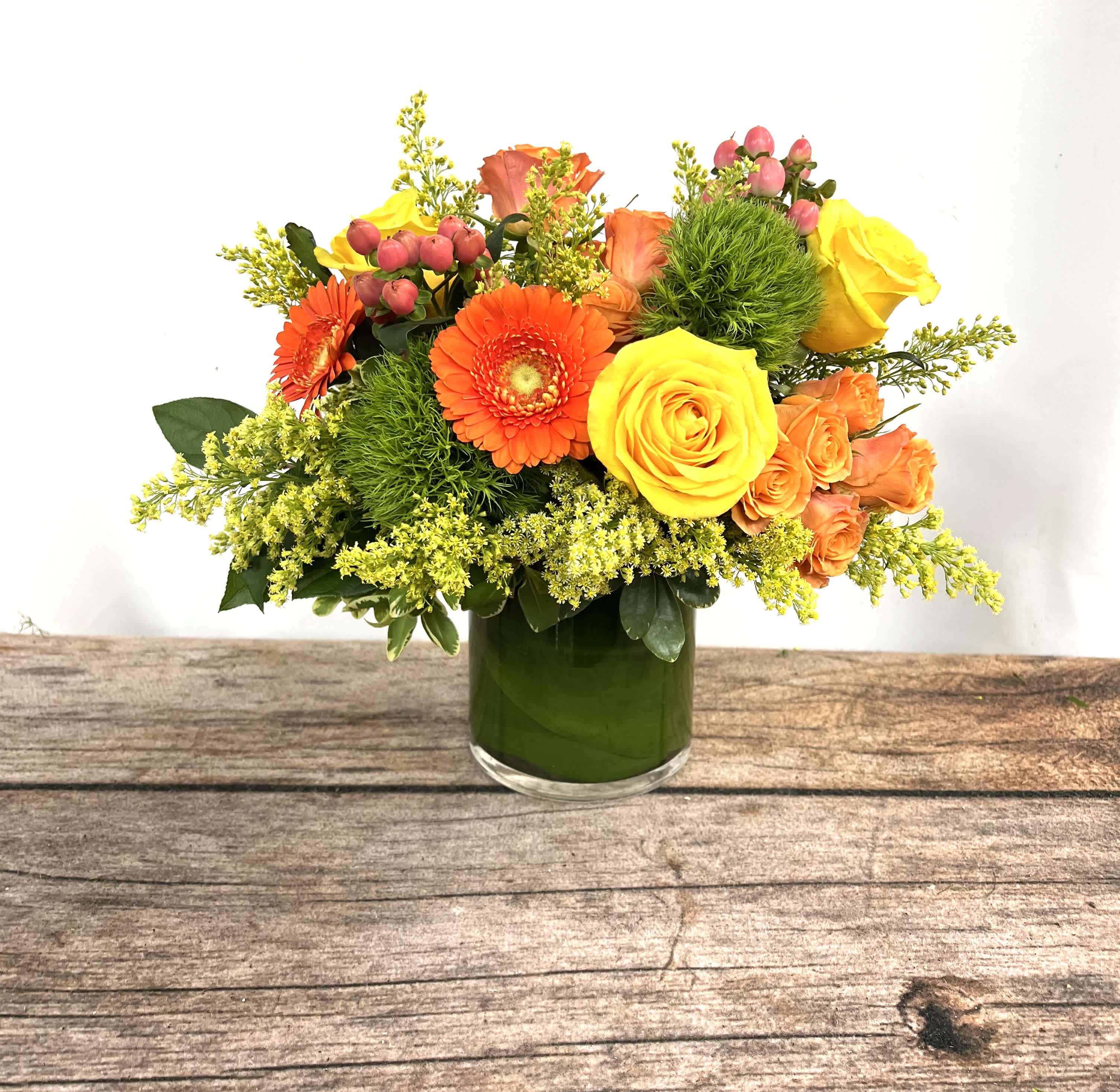 Orange and yellow flowers arranged in a green glass vase