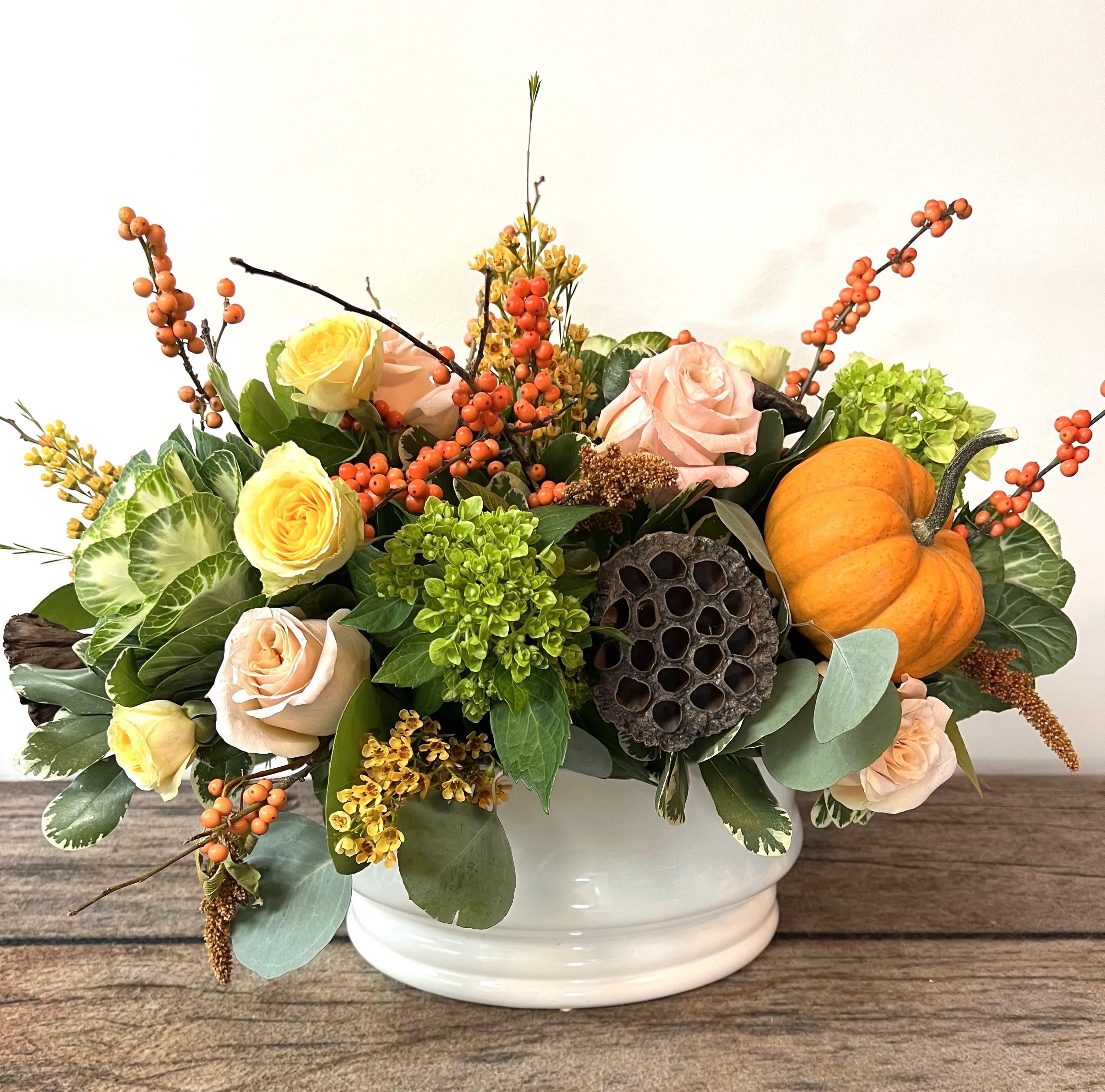 Mixed rose arrangement in a white bowl with a small pumpkin