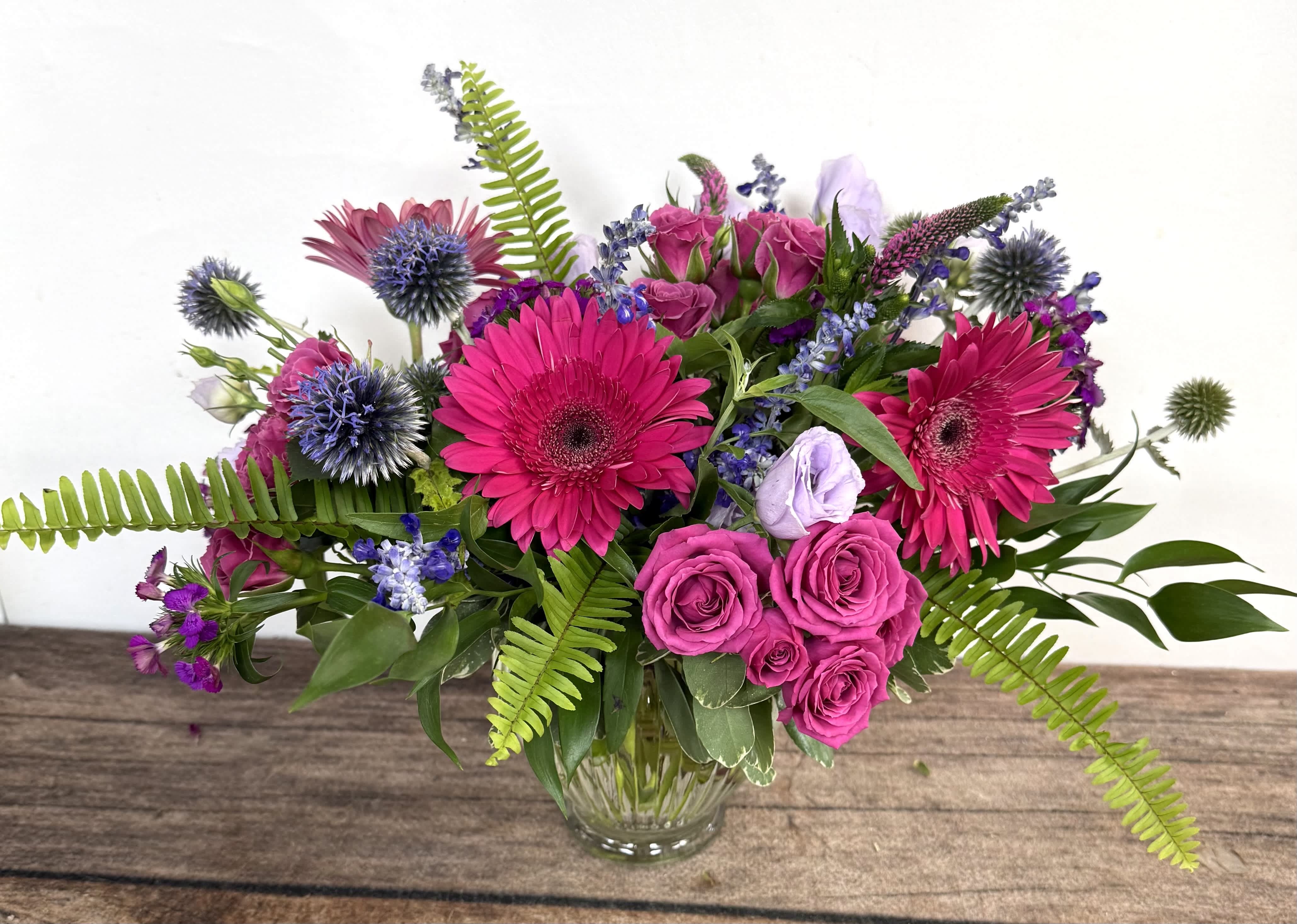 Bouquet of hot pink flowers and purple blooms in a clear glass vase