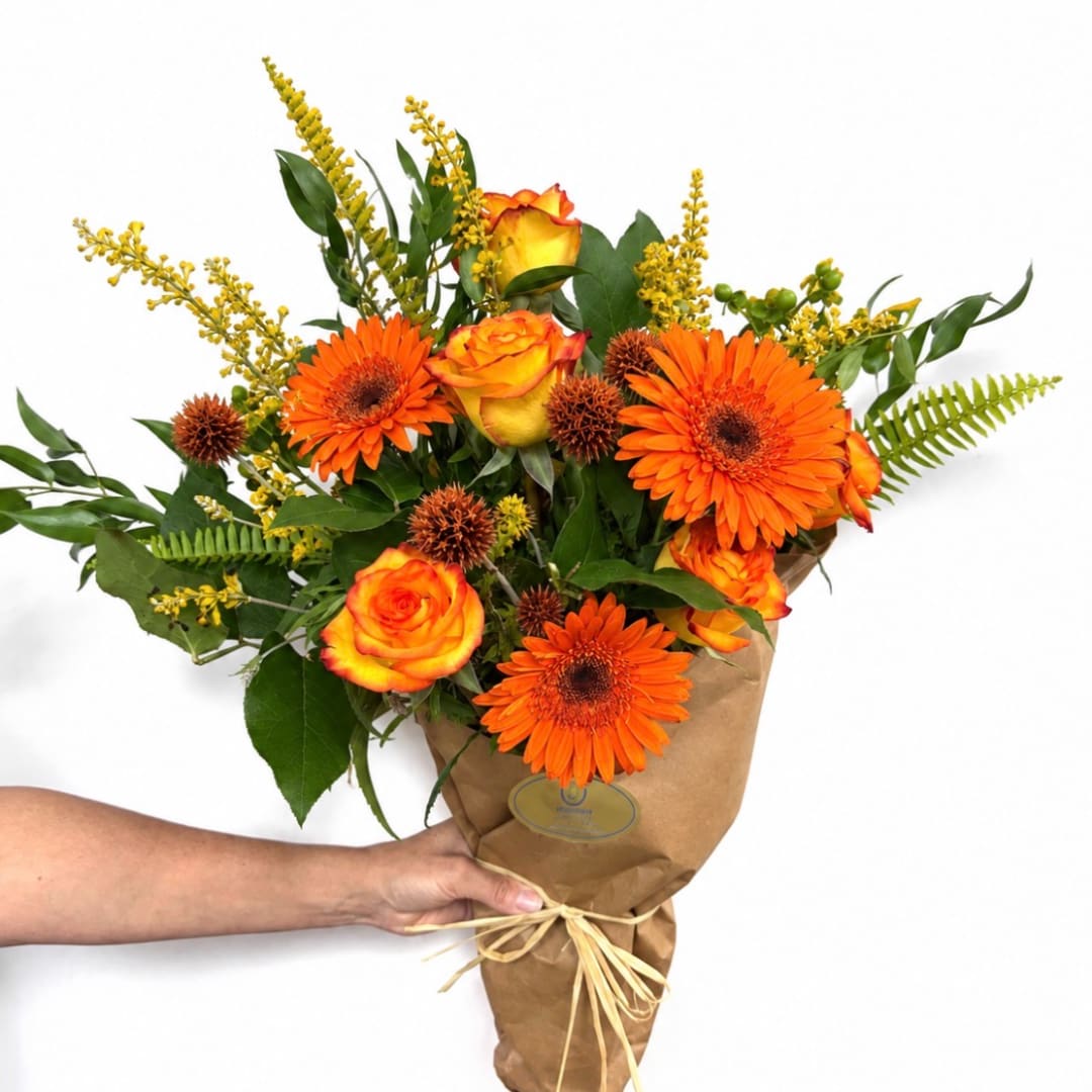 Orange gerbera daisies and roses in brown paper wrapping