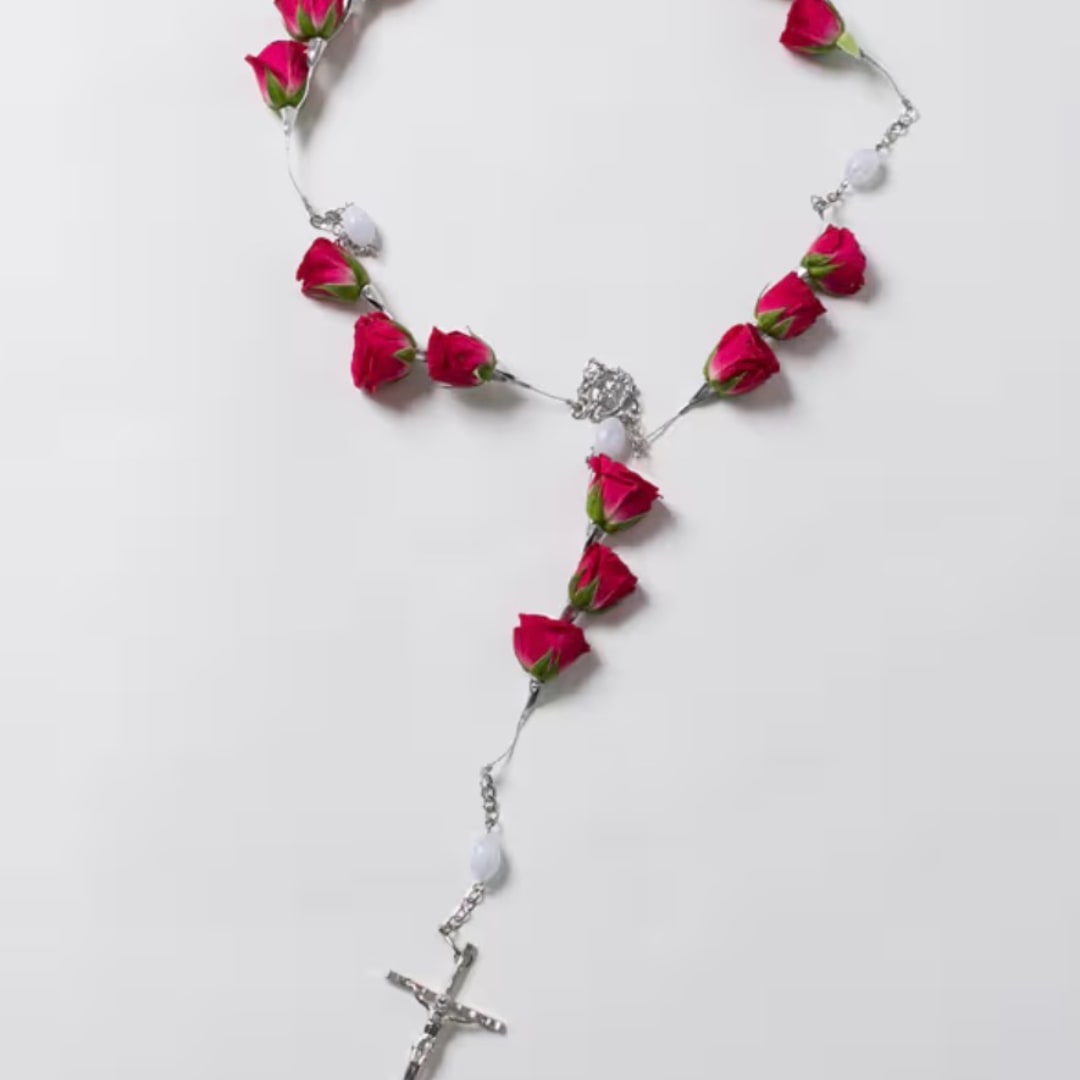 Pink rosebud rosary laid on a white background