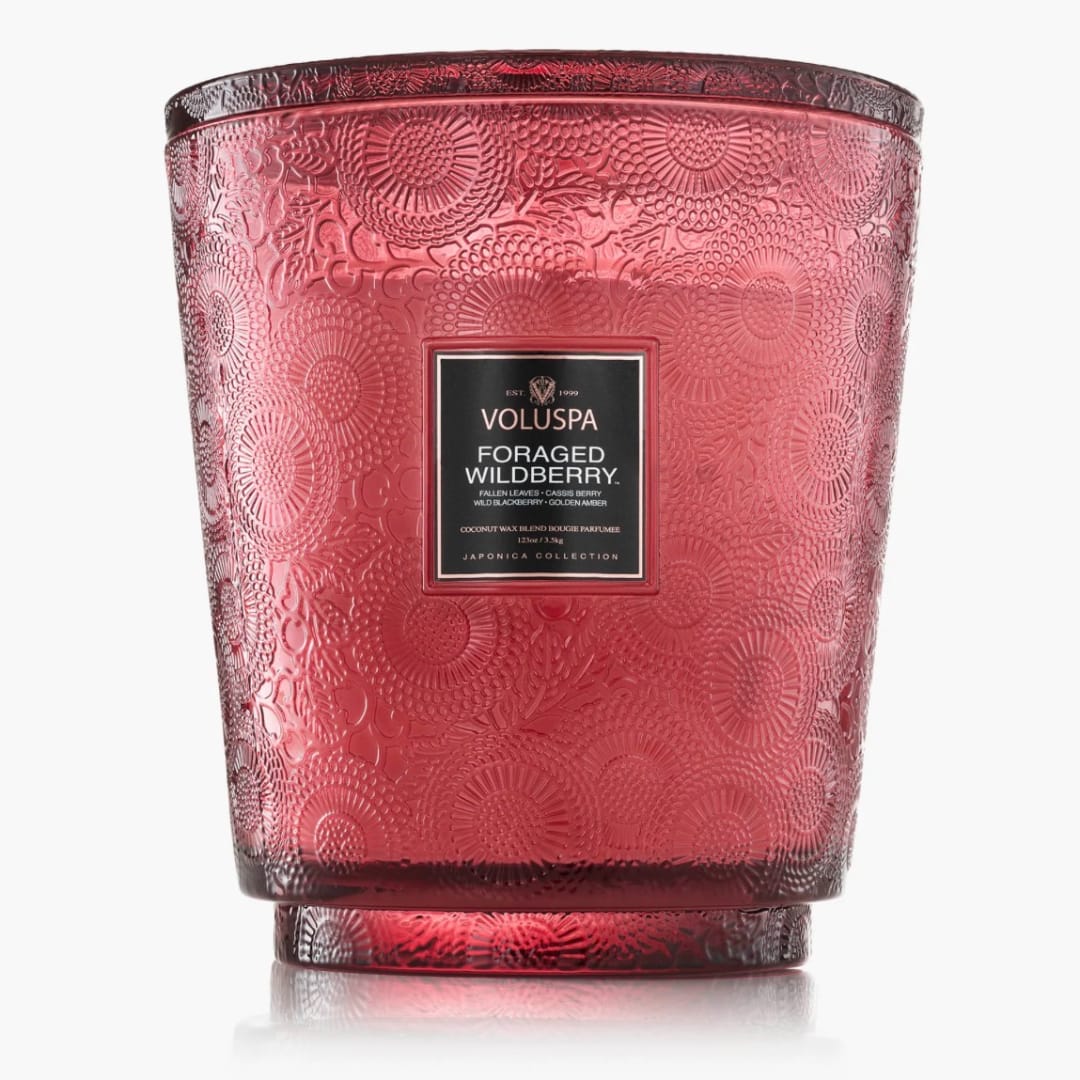 Red patterned glass candle jar with a black label