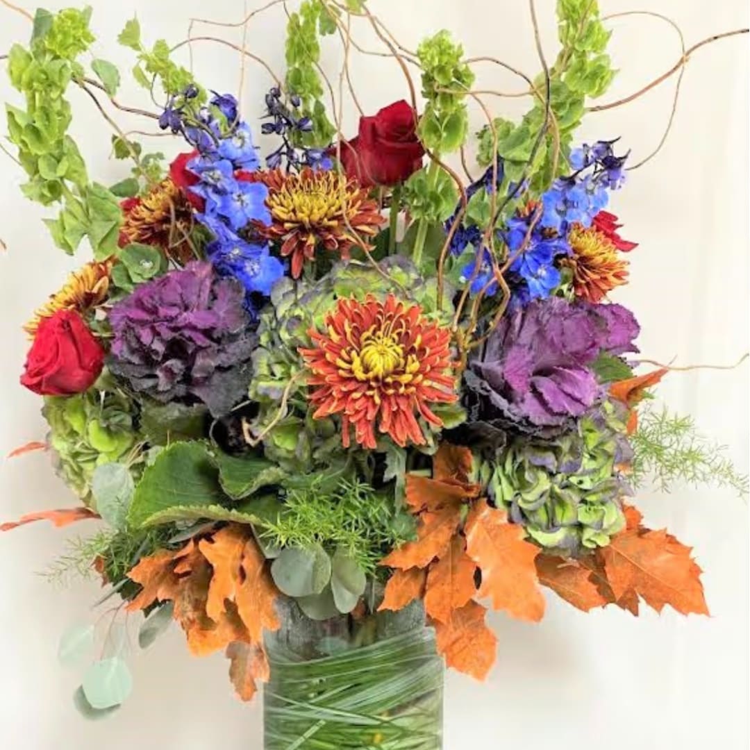 Colorful bouquet with roses, chrysanthemums, and blue flowers in a wrapped vase